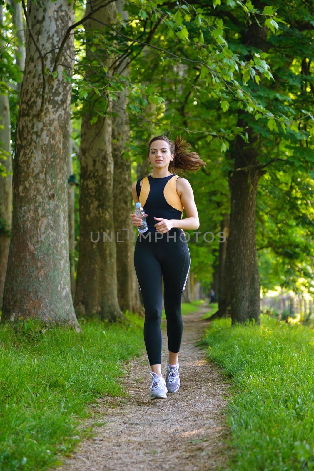 Young beautiful  woman jogging in summer park. Woman in sport outdoors health concept