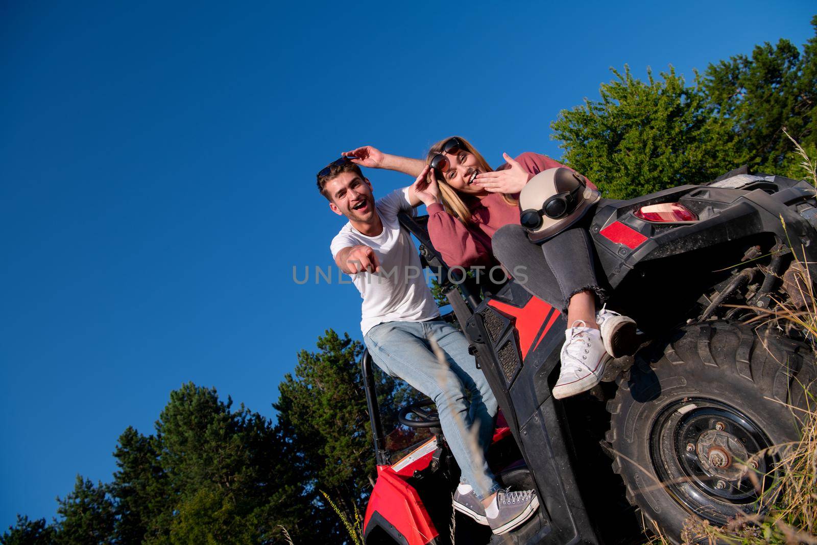 portrait of young happy excited couple enjoying beautiful sunny day while driving a off road buggy car on mountain nature