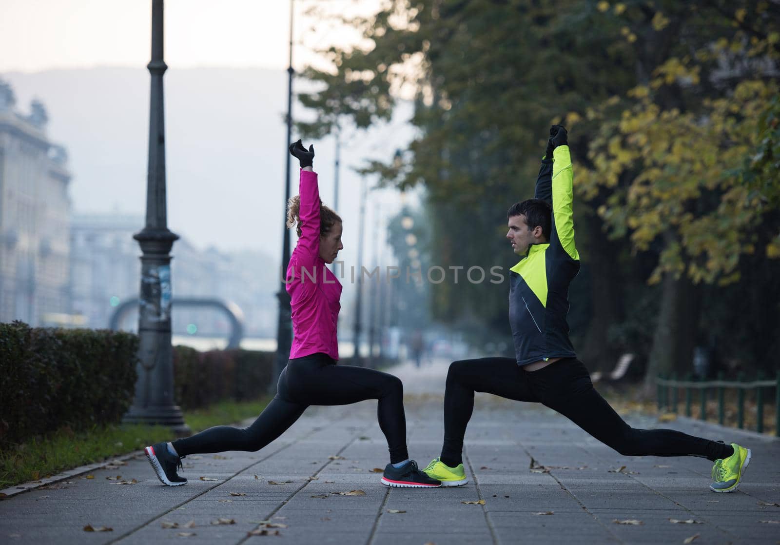 jogging couple warming up and stretching before morning running in the city