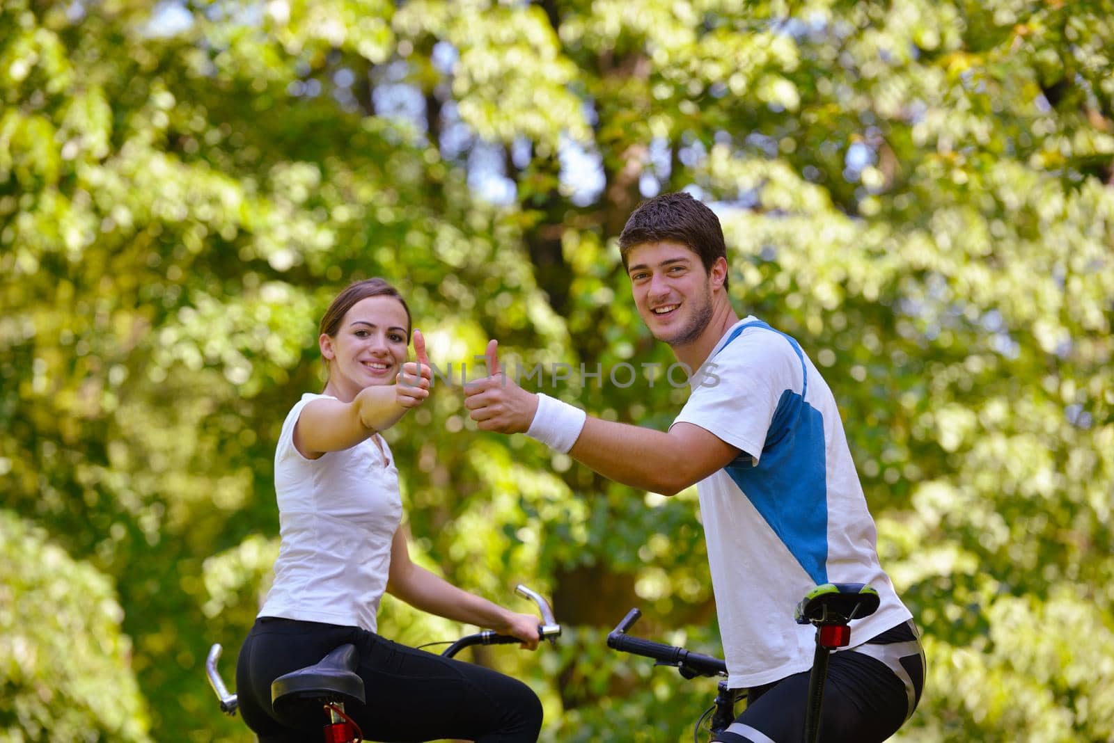 Happy couple ridine bicycle outdoors by dotshock