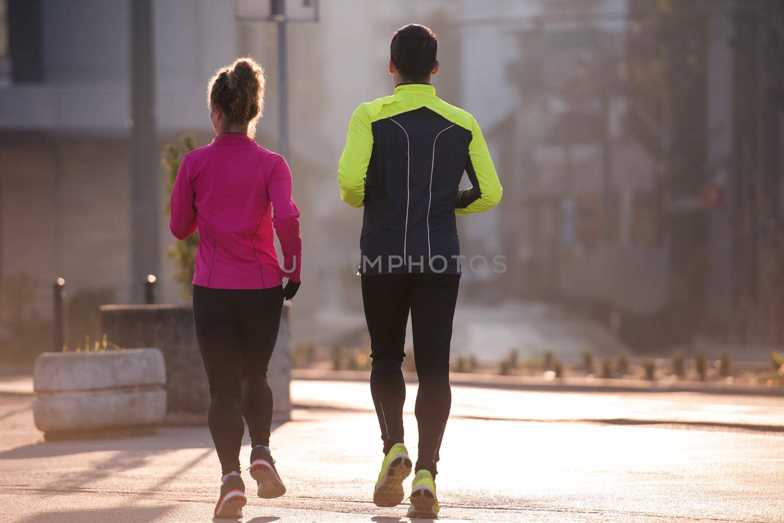 healthy young  couple jogging in the city  at early morning with sunrise in background