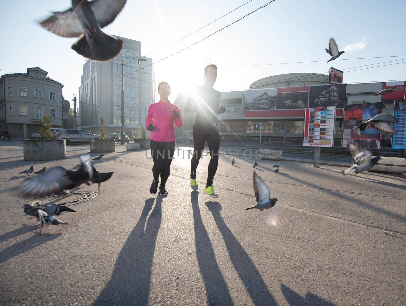 healthy young  couple jogging in the city  at early morning with sunrise in background