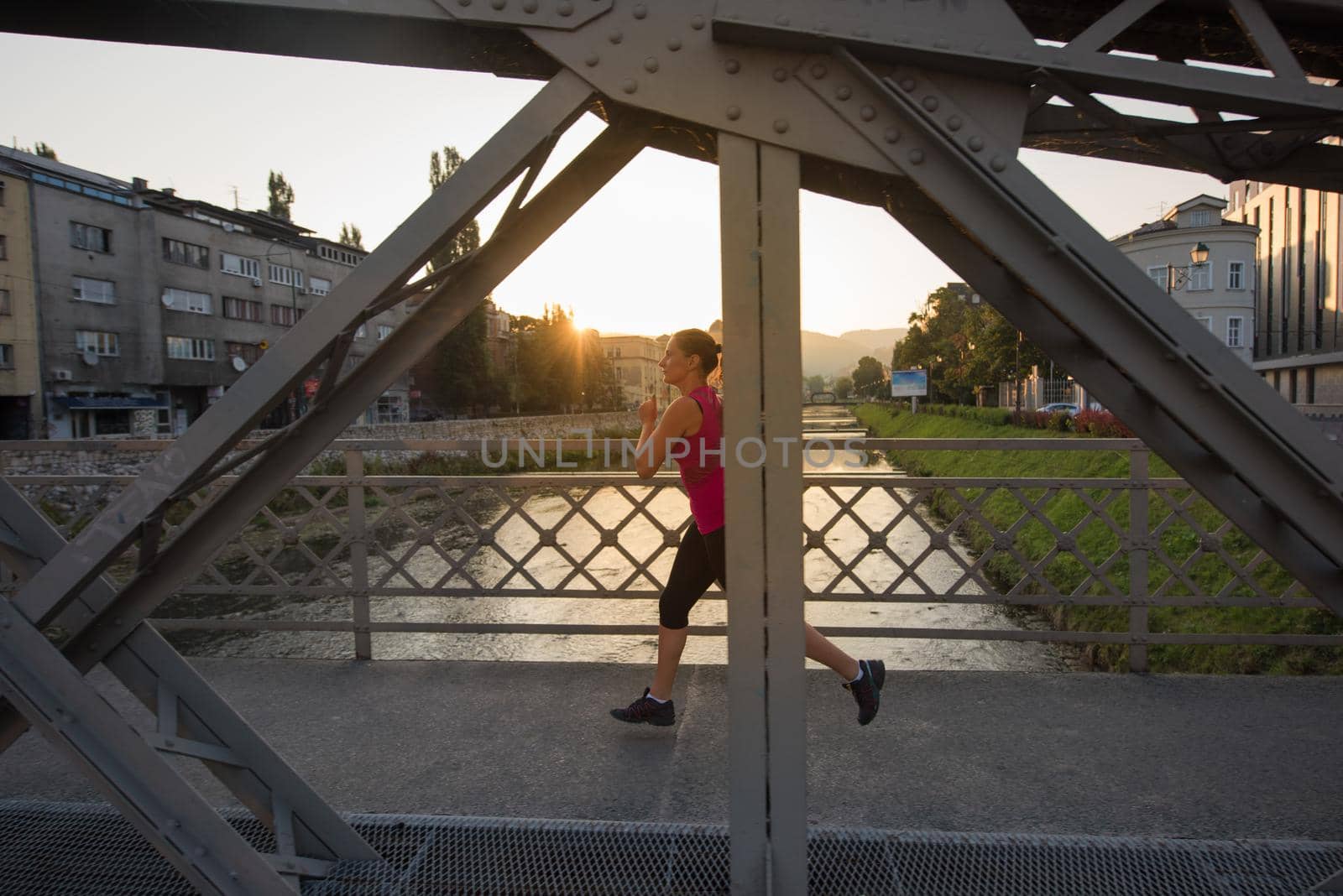 woman jogging across the bridge at sunny morning by dotshock