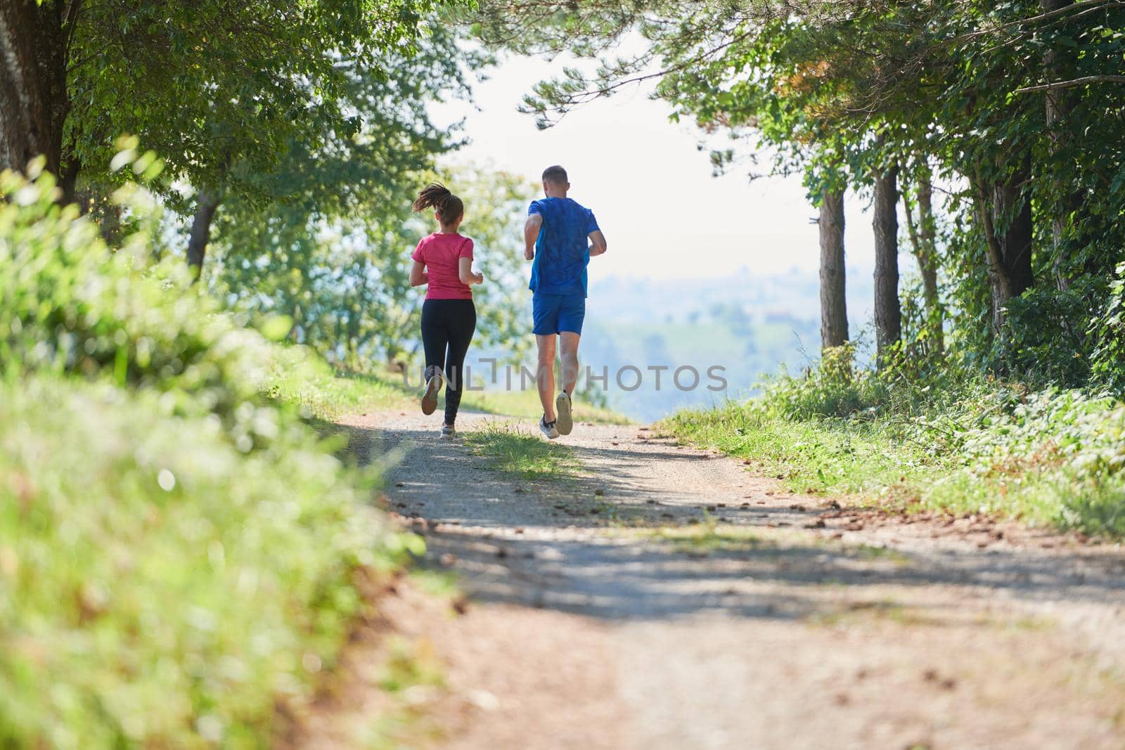 couple enjoying in a healthy lifestyle while jogging on a country road by dotshock