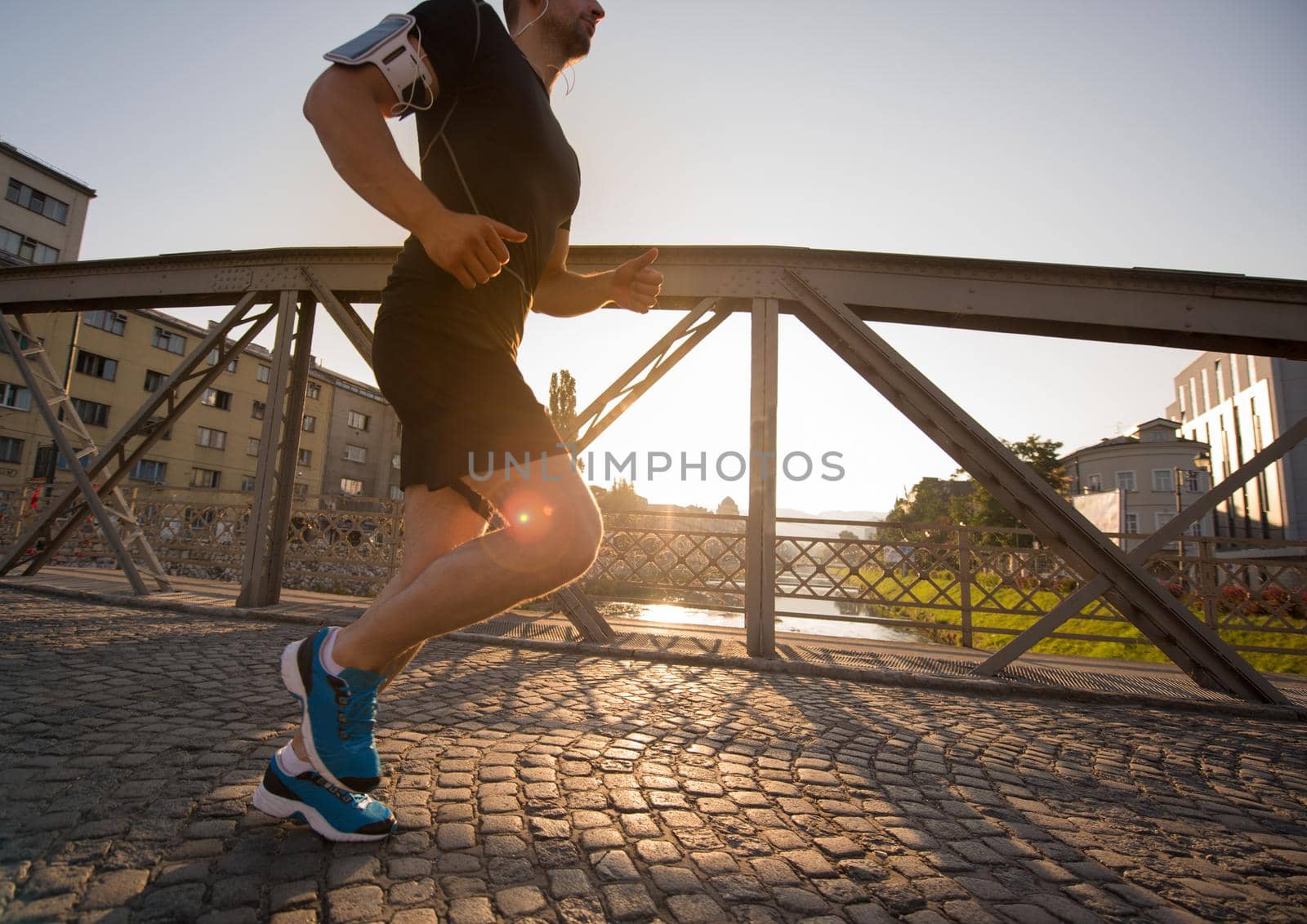 man jogging across the bridge at sunny morning by dotshock