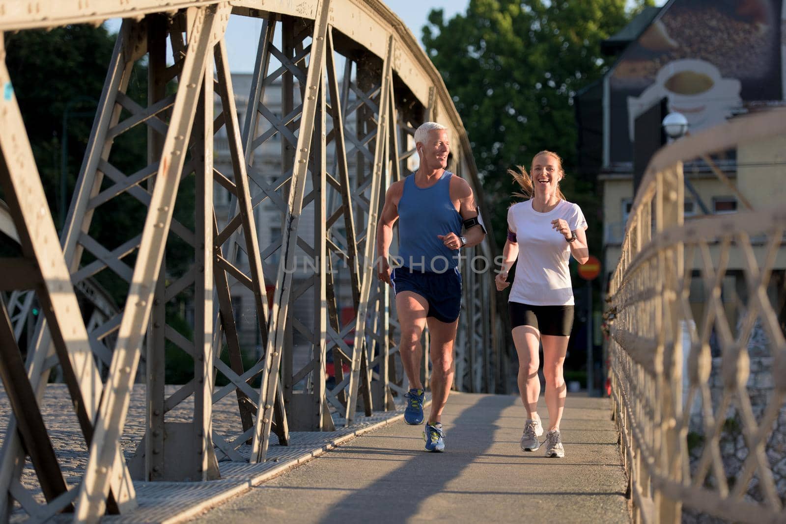 healthy mature couple jogging in the city  at early morning with sunrise in background