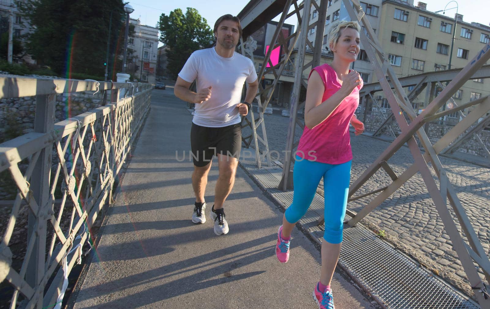 healthy mature couple jogging in the city  at early morning with sunrise in background