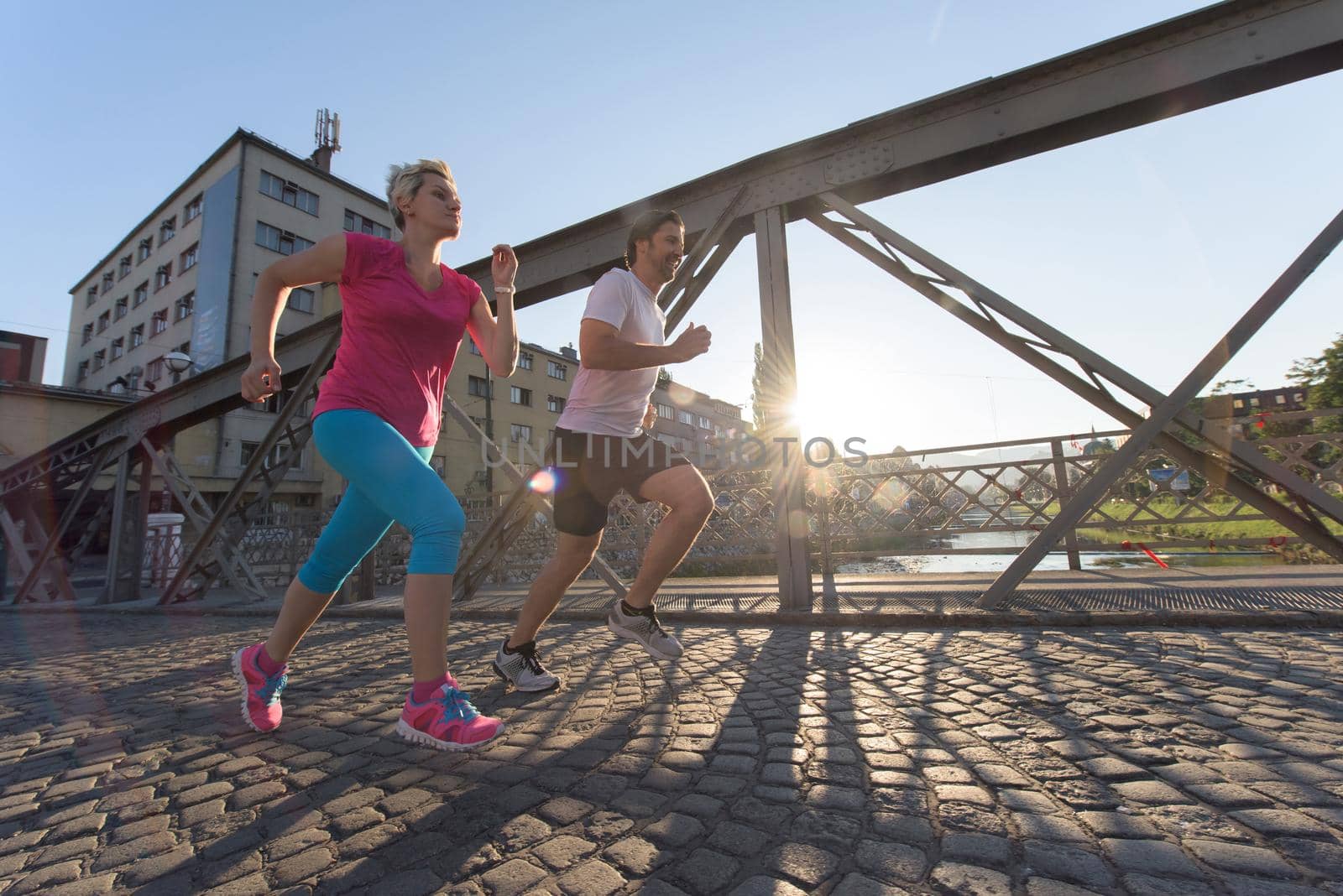 healthy mature couple jogging in the city  at early morning with sunrise in background