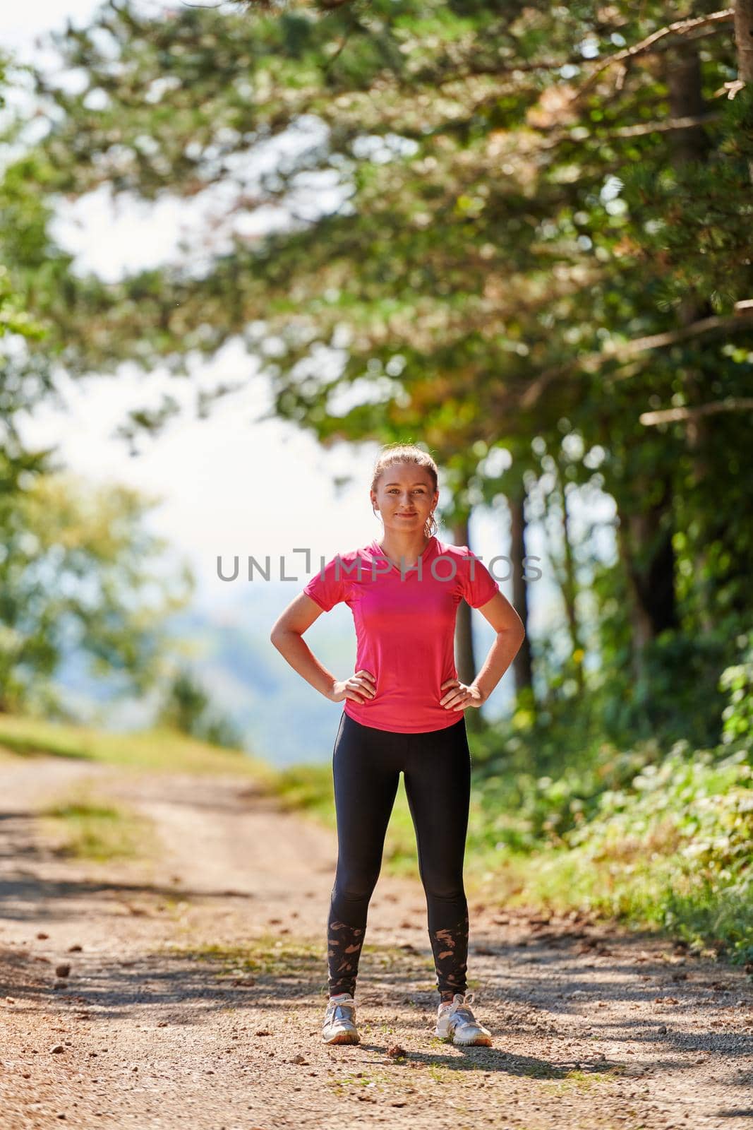 woman enjoying in a healthy lifestyle while jogging on a country road through the beautiful sunny forest, exercise and fitness concept
