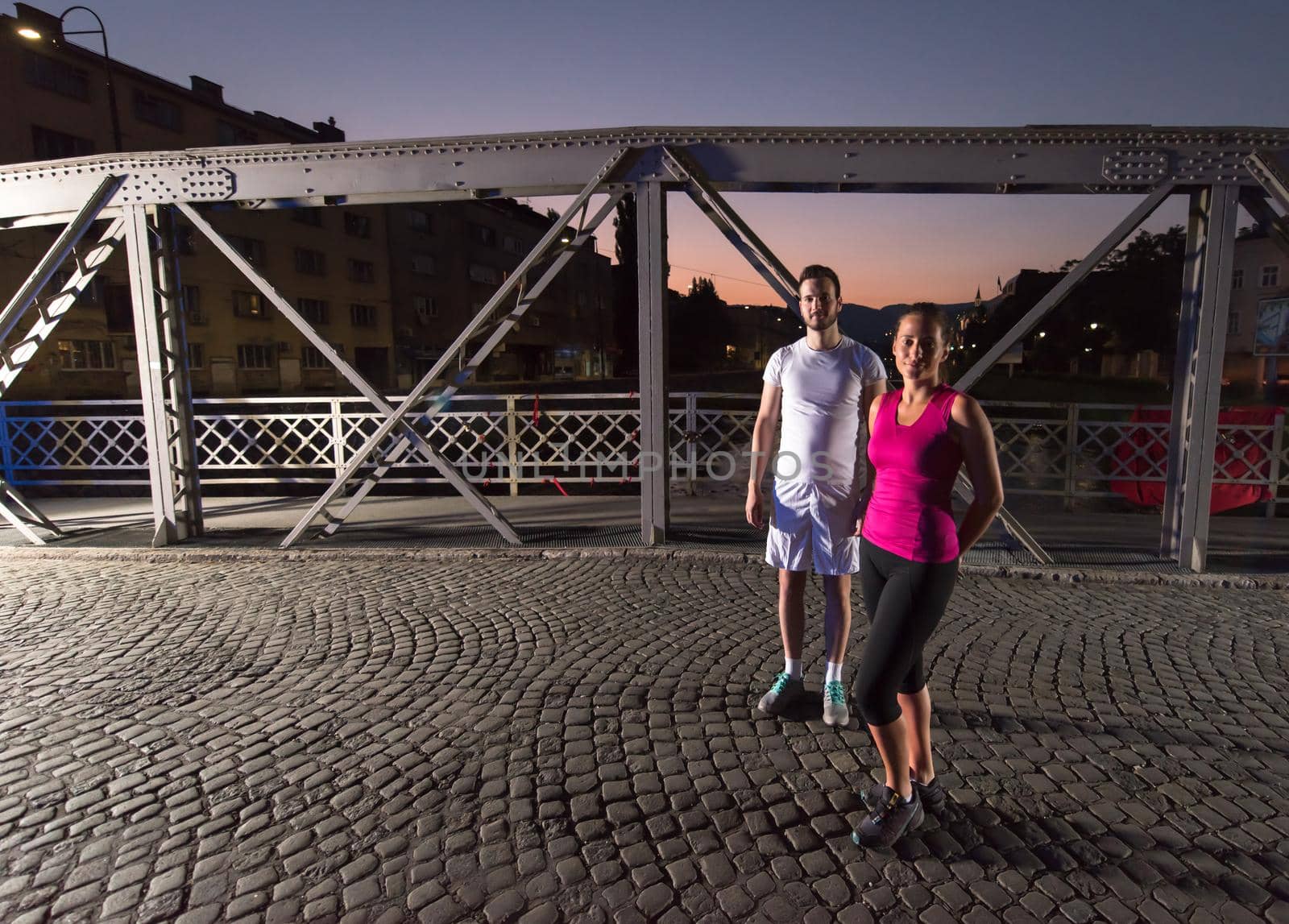 couple jogging across the bridge in the city by dotshock
