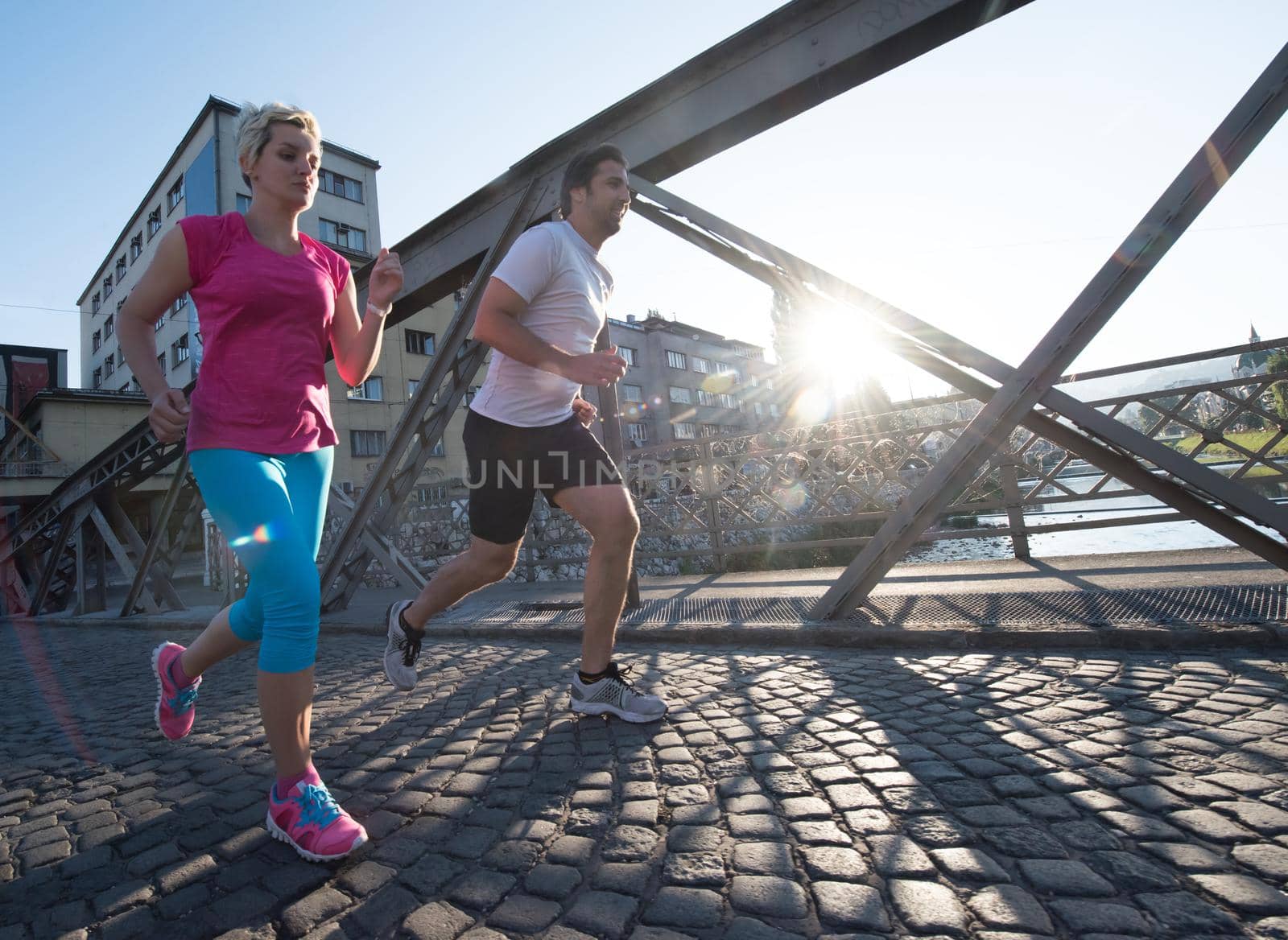 healthy mature couple jogging in the city  at early morning with sunrise in background