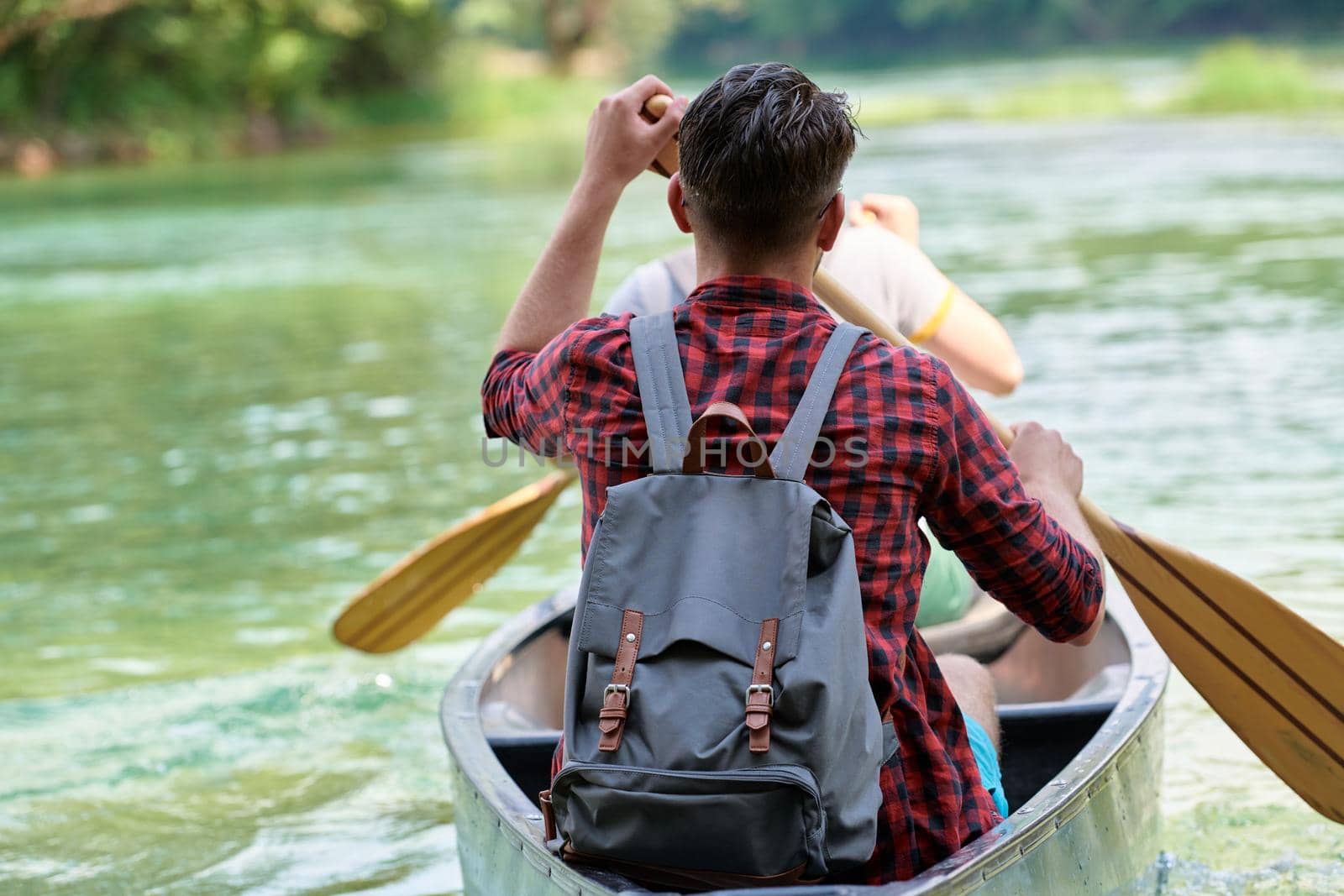 Couple adventurous explorer friends are canoeing in a wild river surrounded by the beautiful nature