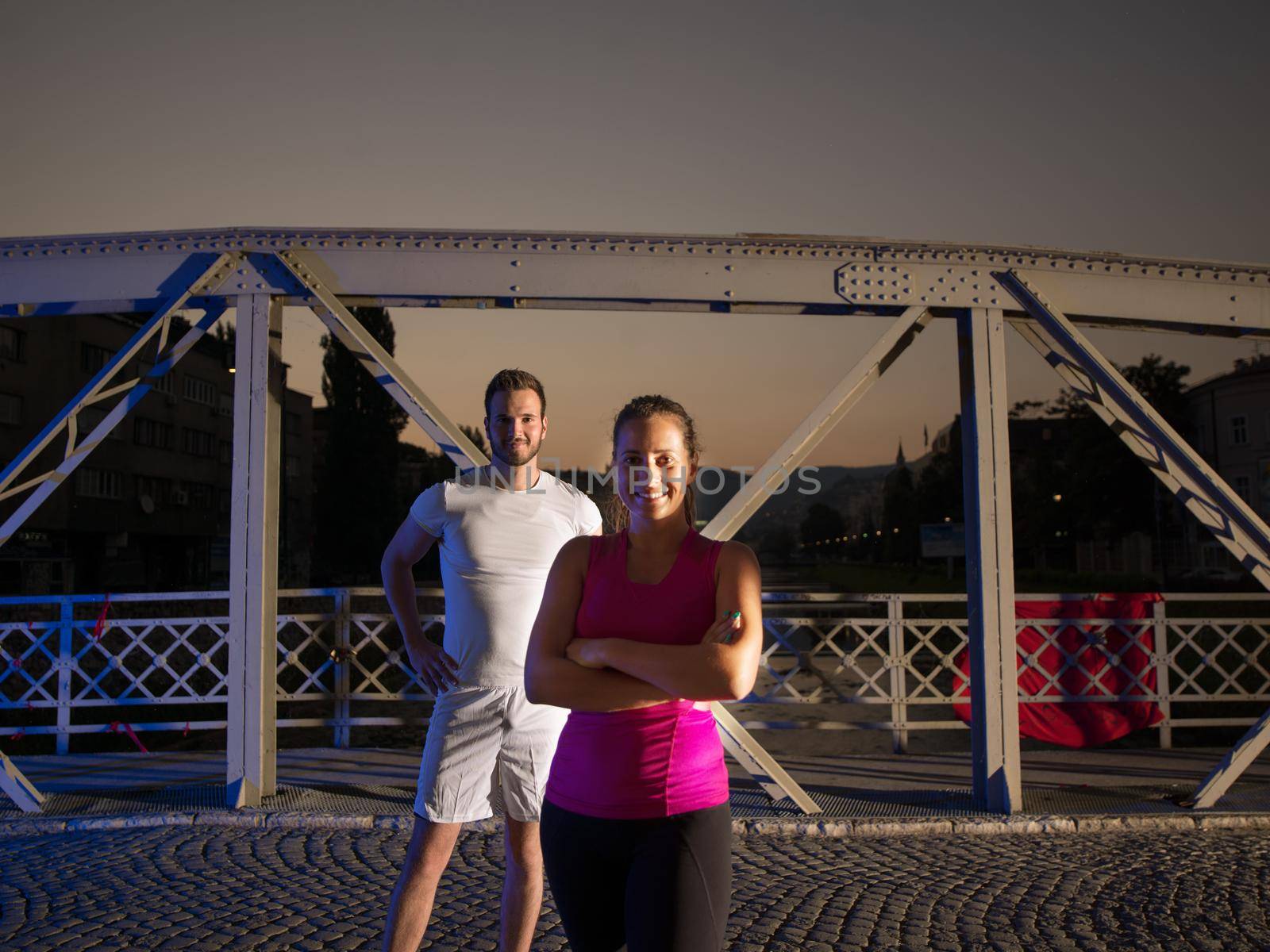 urban sports, portrait of a healthy couple jogging across the bridge in the city at early morning in night