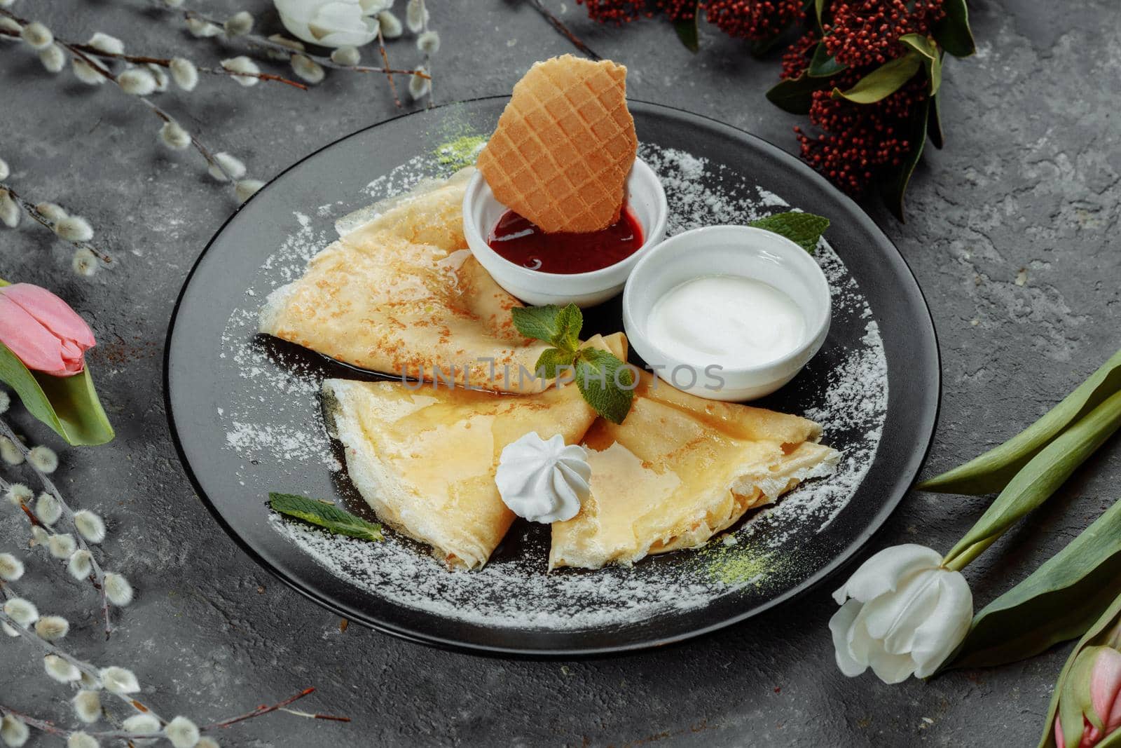 Pancakes with strawberries and creme black plate.