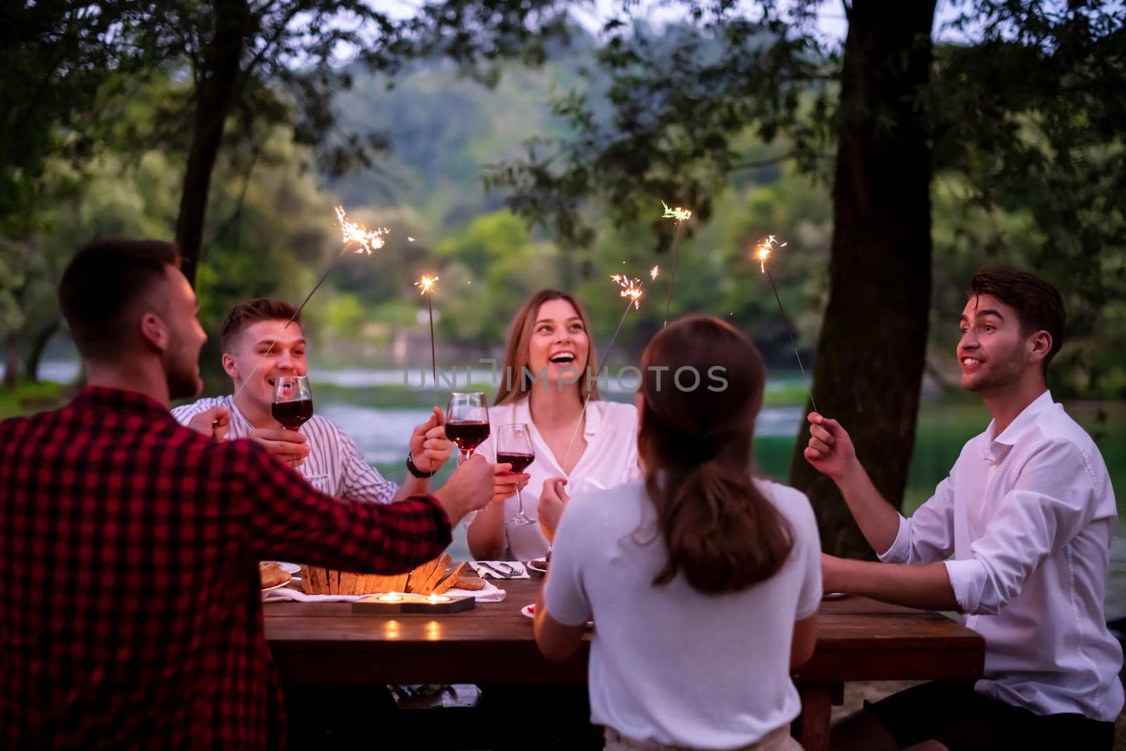 happy friends having french dinner party outdoor by dotshock