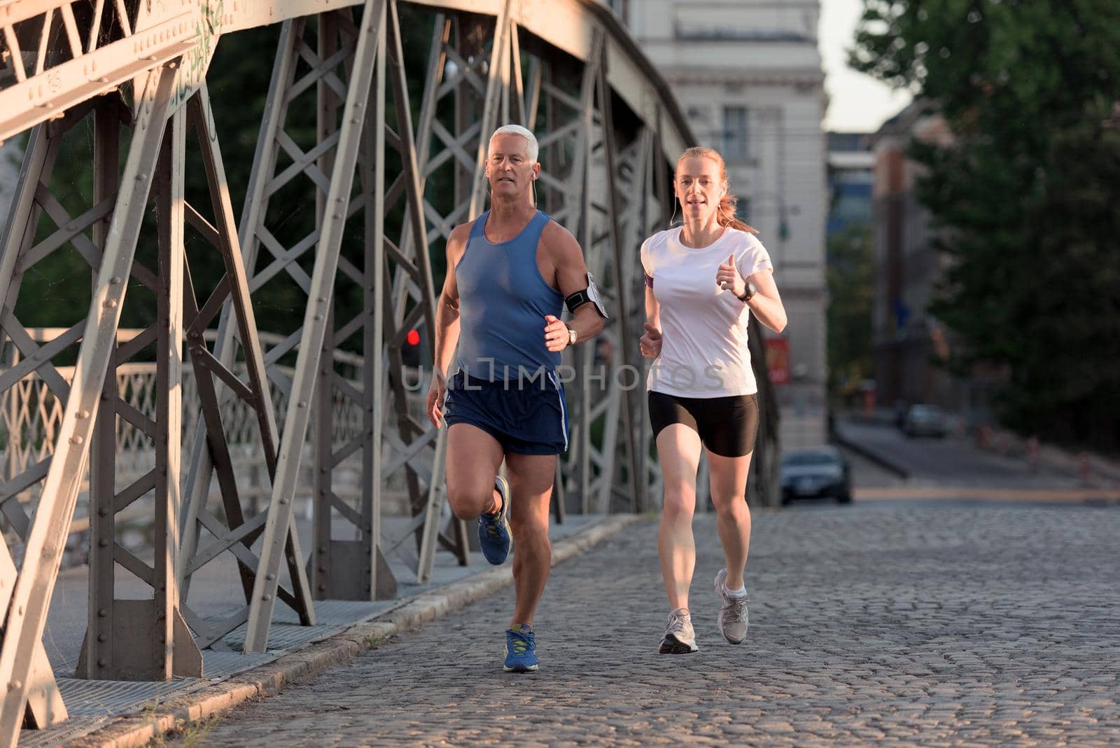 healthy mature couple jogging in the city  at early morning with sunrise in background