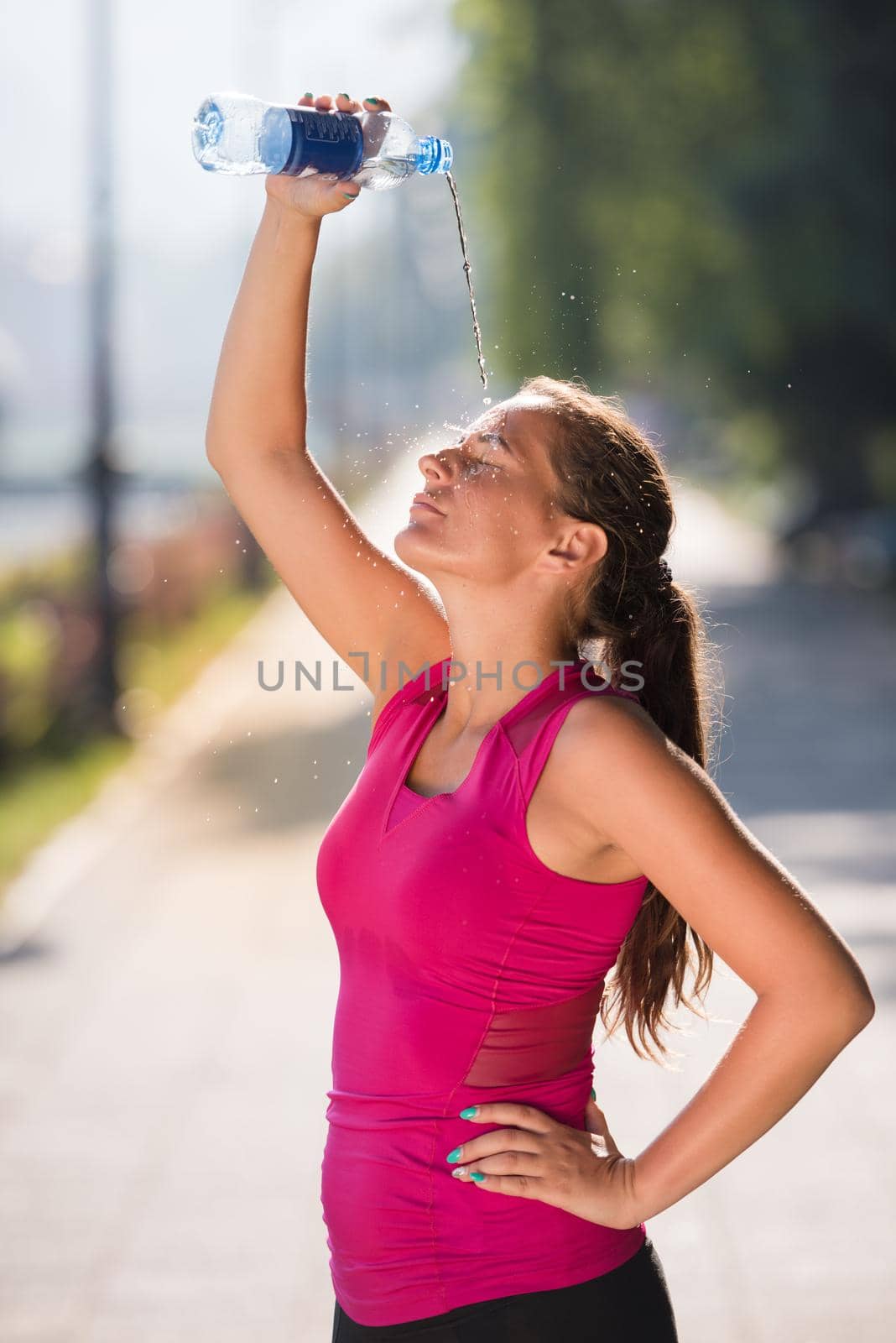 woman pouring water from bottle on her head by dotshock