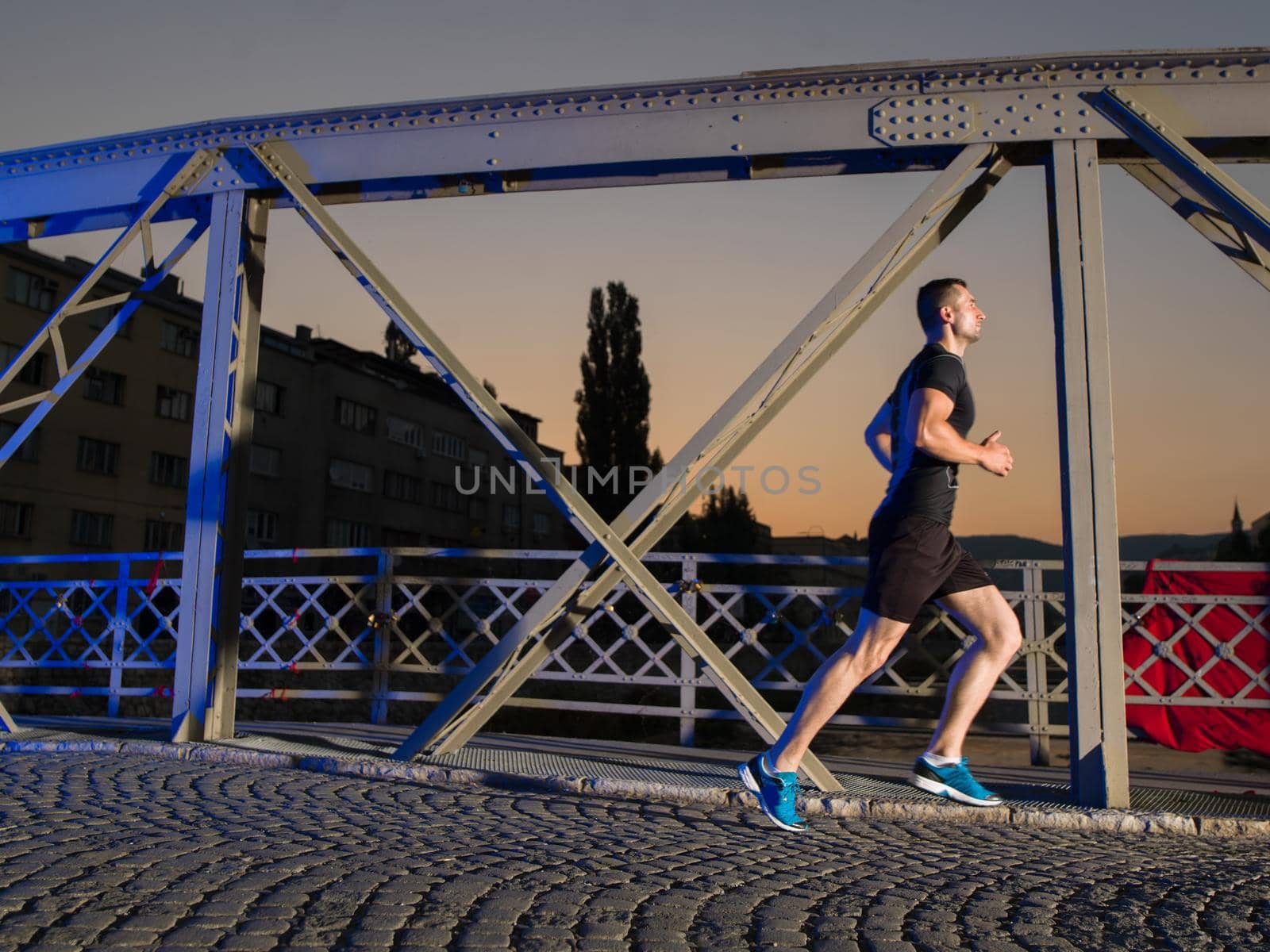 man jogging across the bridge in the city by dotshock