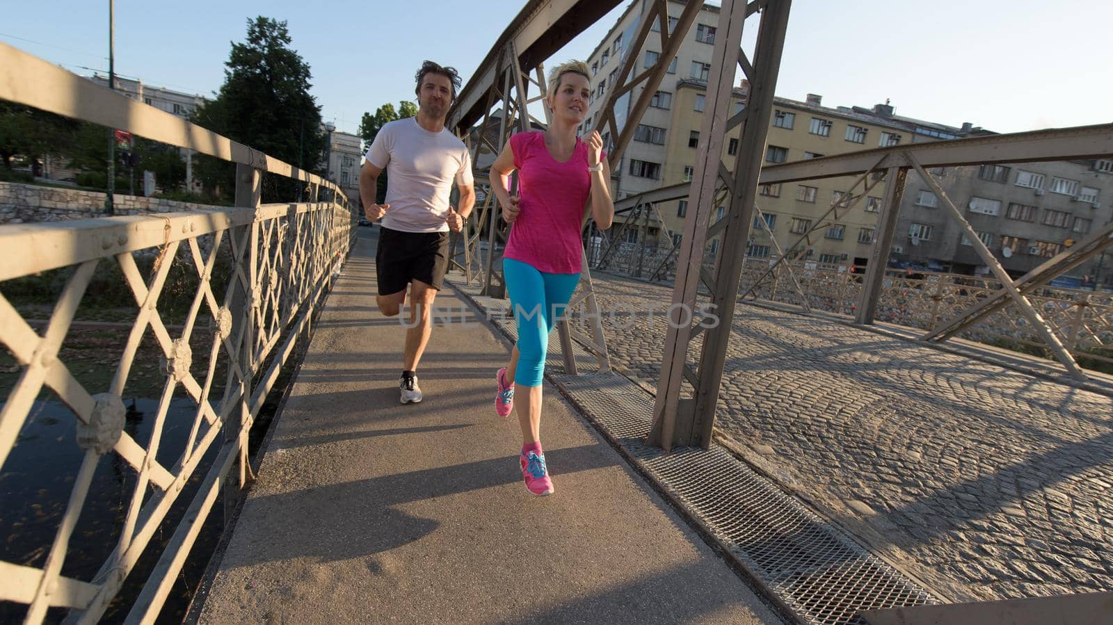 healthy mature couple jogging in the city  at early morning with sunrise in background