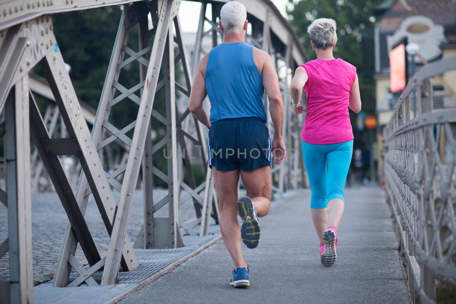 healthy mature couple jogging in the city  at early morning with sunrise in background