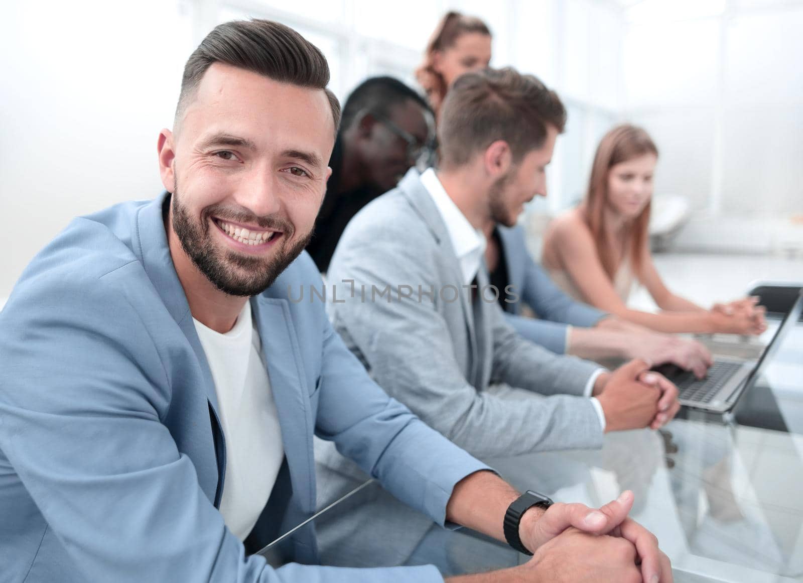 european man smiling and sitting with colleagues in the office