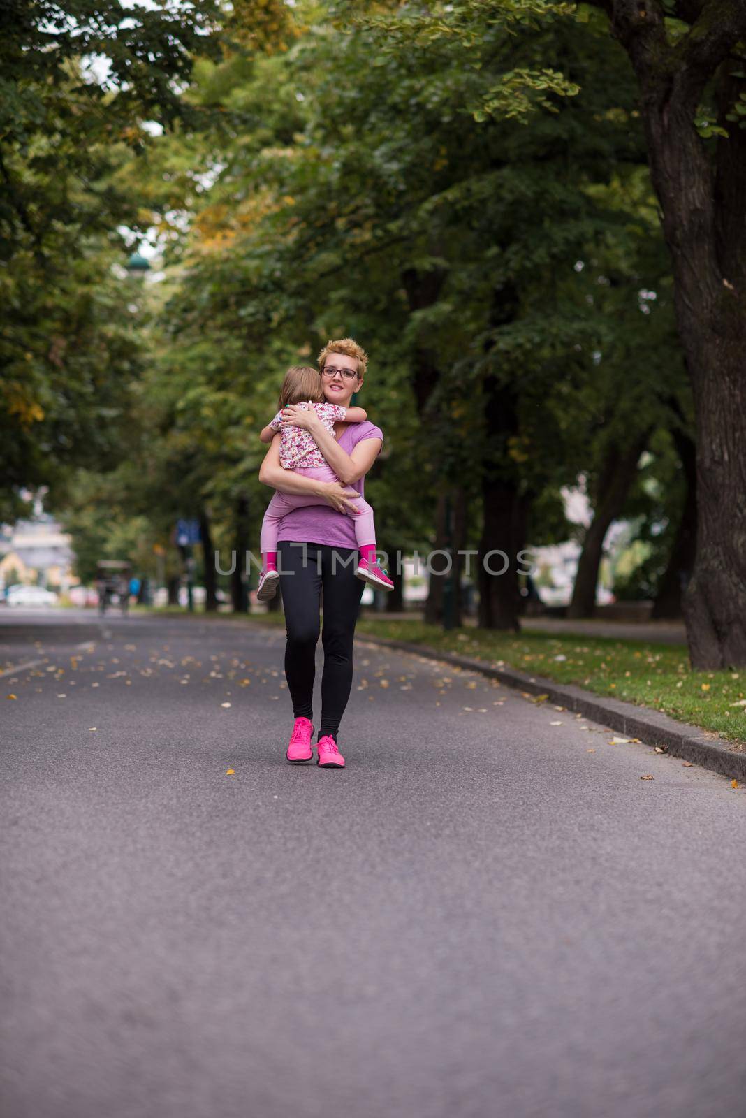 jogging mother carries little daughter by dotshock