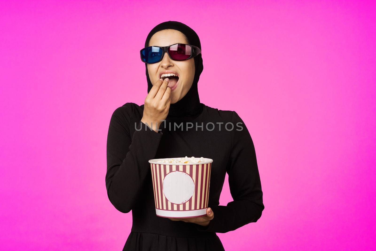 Muslim woman attractive look popcorn glasses movie watching studio lifestyle. High quality photo