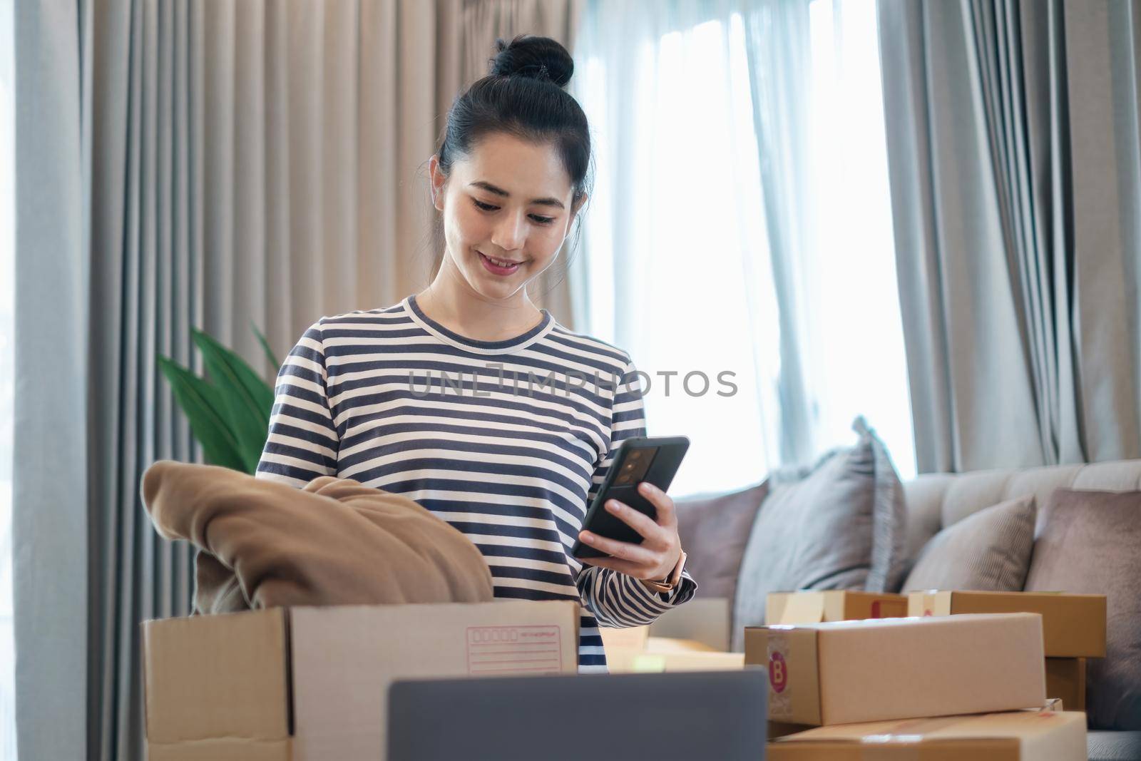 Asian small business owner checking order by smartphone at home office. Business retail market and online sell marketing delivery, SME e-commerce concept. by itchaznong