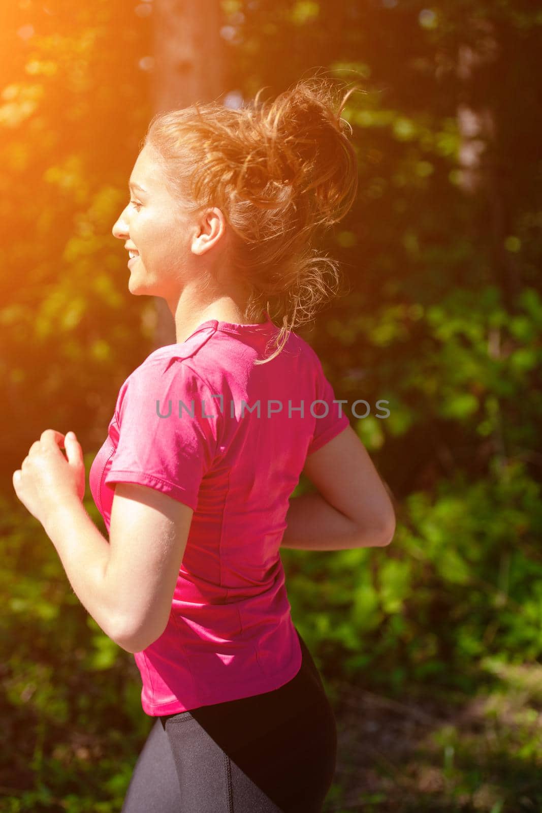 young happy woman enjoying in a healthy lifestyle while jogging on a country road through the beautiful sunny forest, exercise and fitness concept