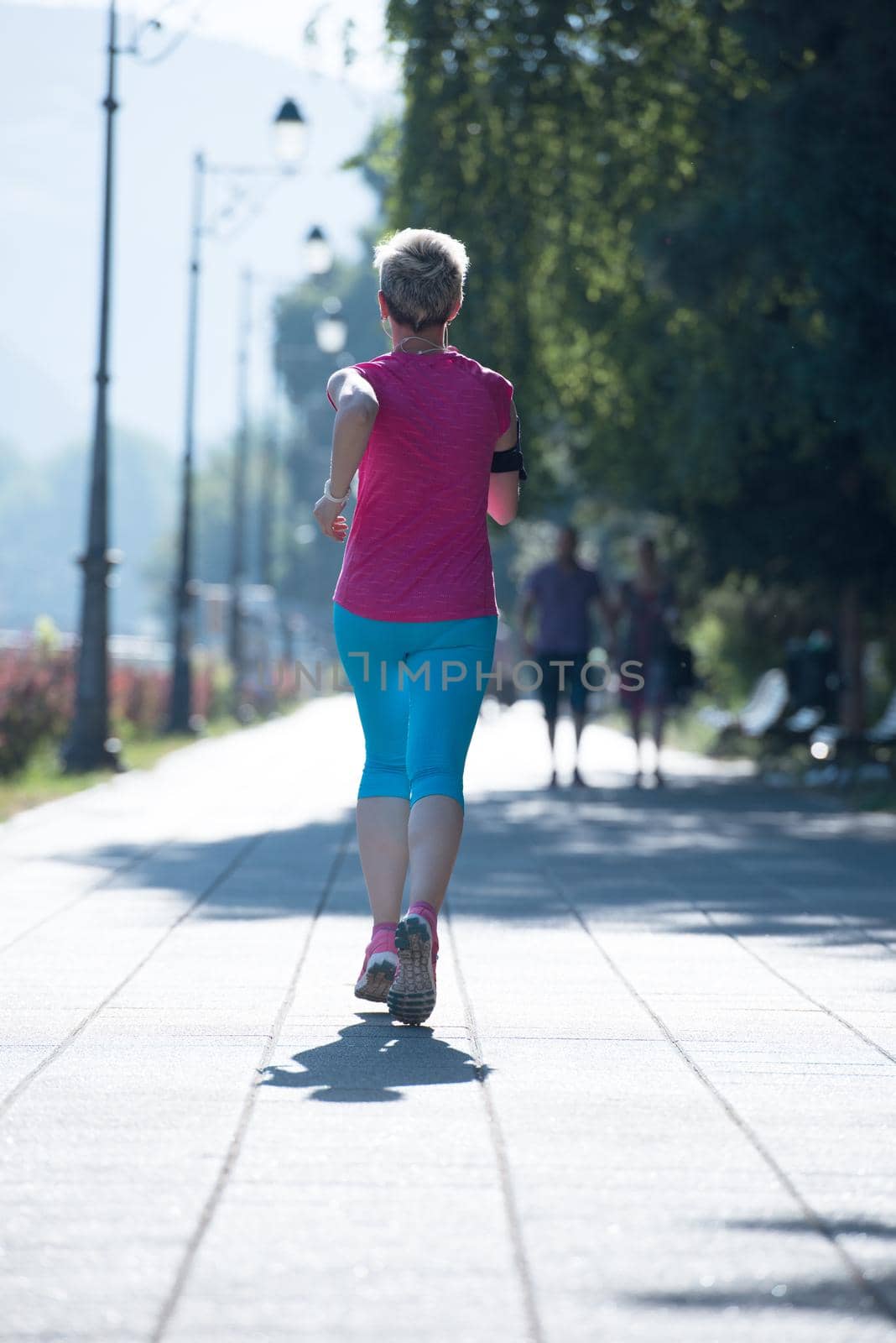 sporty woman running  on sidewalk by dotshock