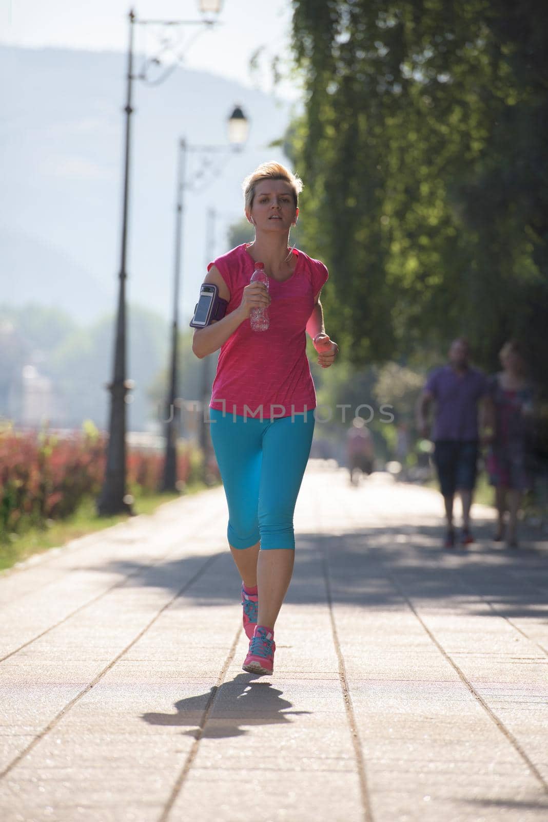 sporty woman running on sidewalk at early morning with city  sunrise scene in background