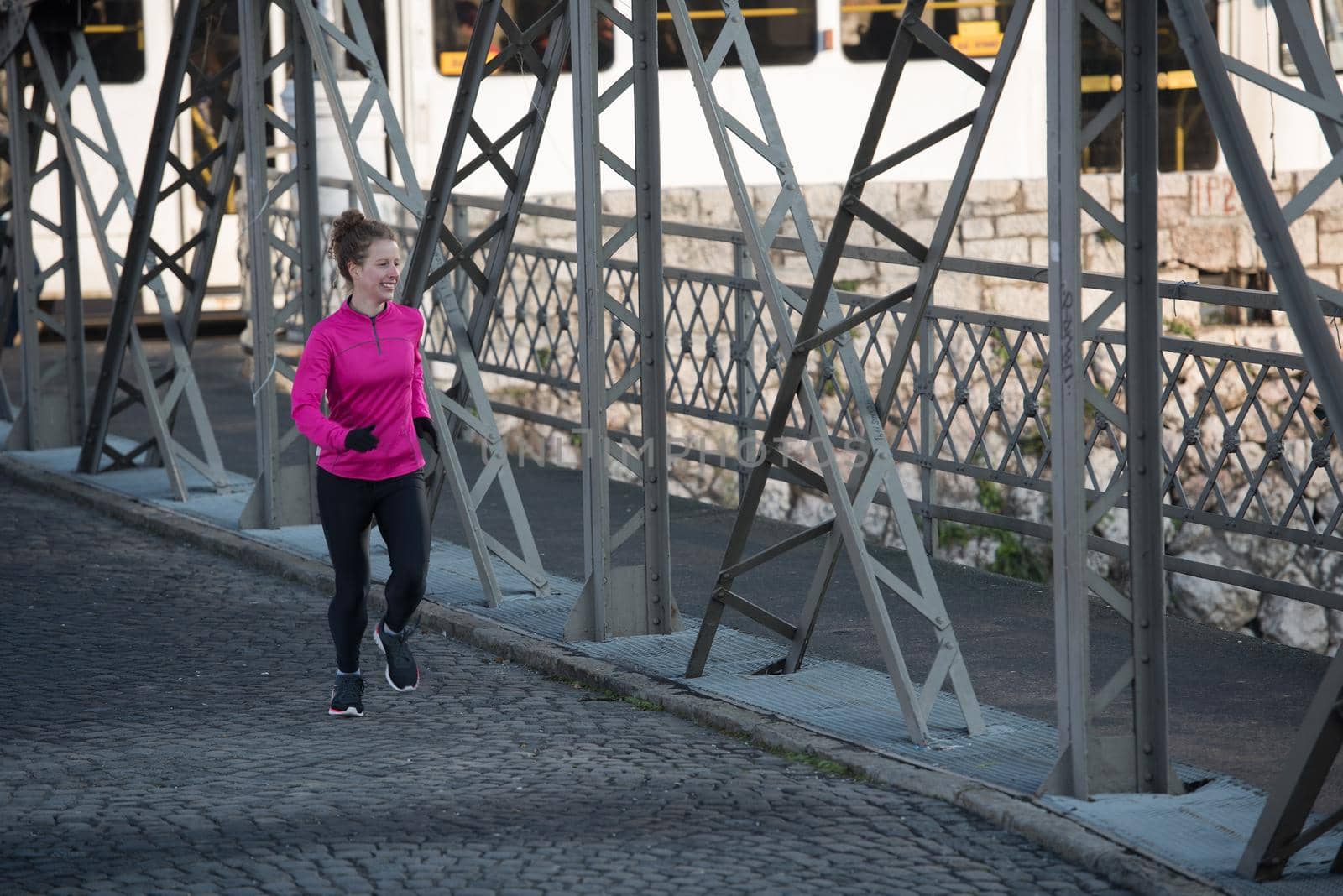 sporty woman running on sidewalk at early morning jogging with city  sunrise scene in background