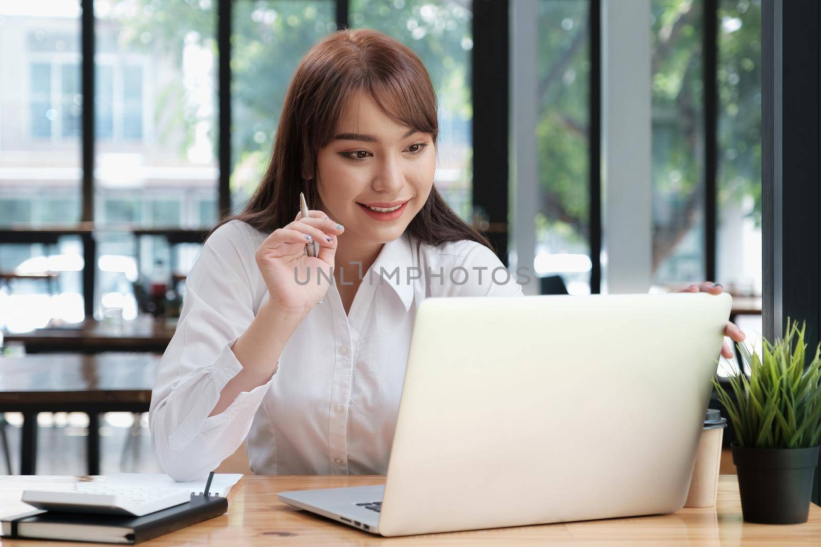 Cheerful young asian woman using laptop computer at home. Student female in living room. online learning, studying , online shopping, freelance, asean concept.