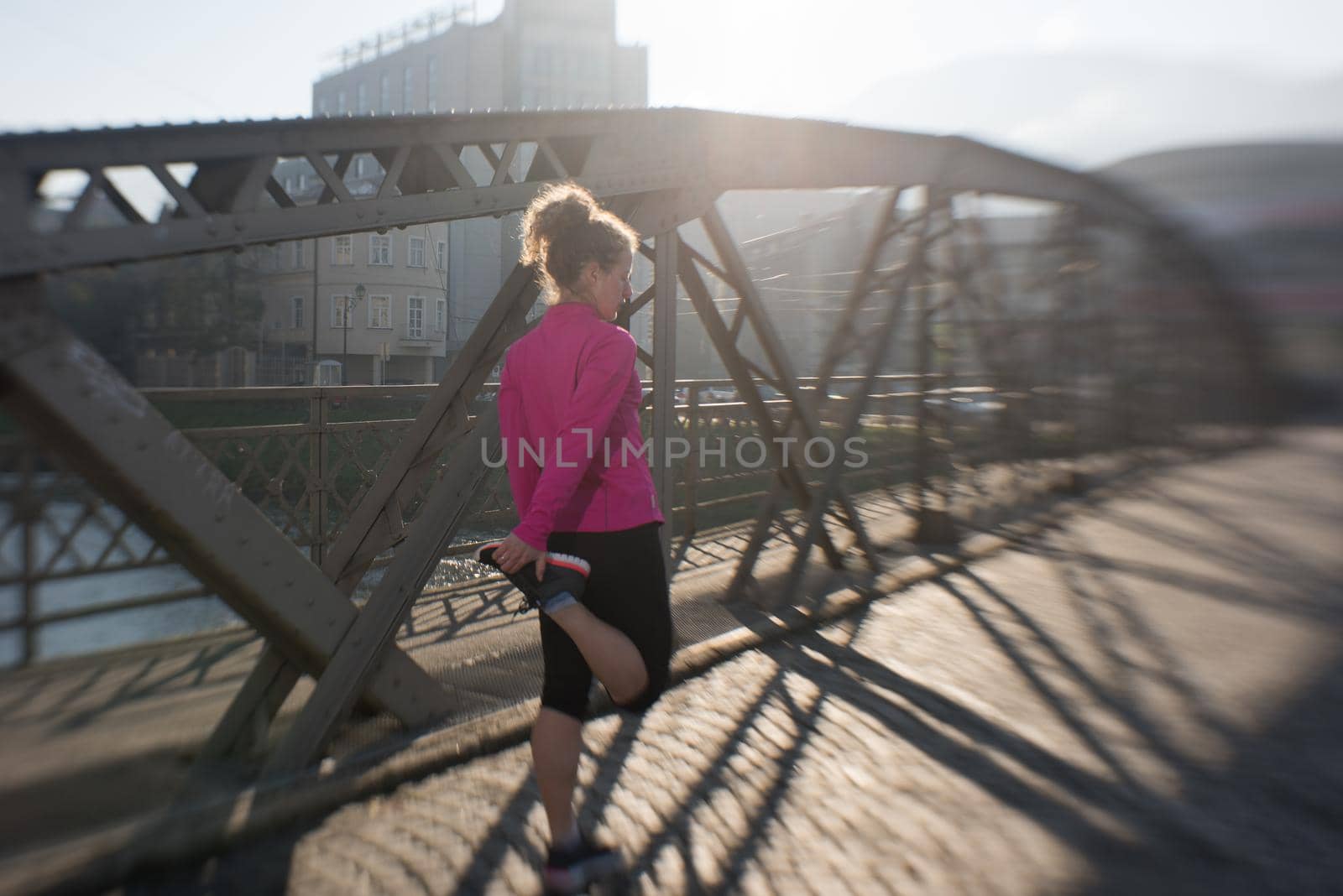 sporty woman running on sidewalk at early morning jogging with city  sunrise scene in background