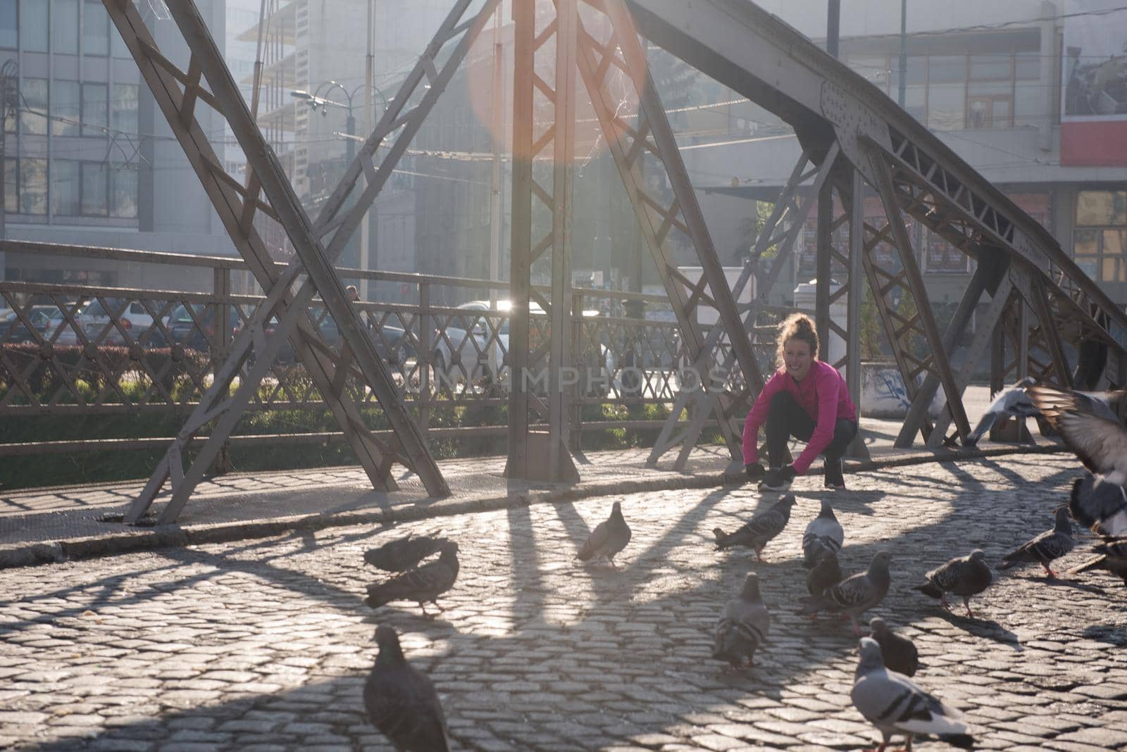 sporty woman running on sidewalk at early morning jogging with city  sunrise scene in background