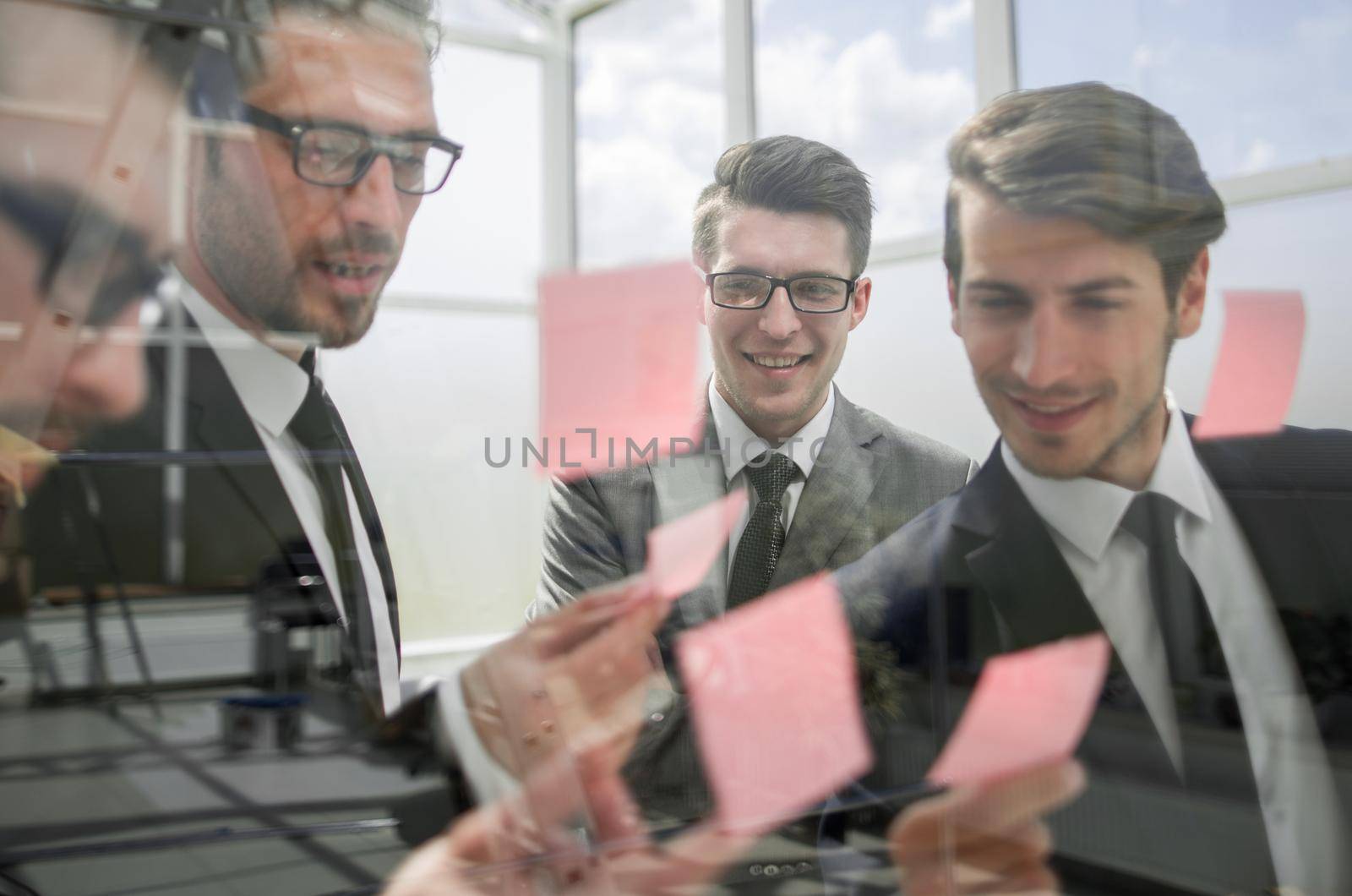 business team reading sticky notes on glass.the concept of a startup