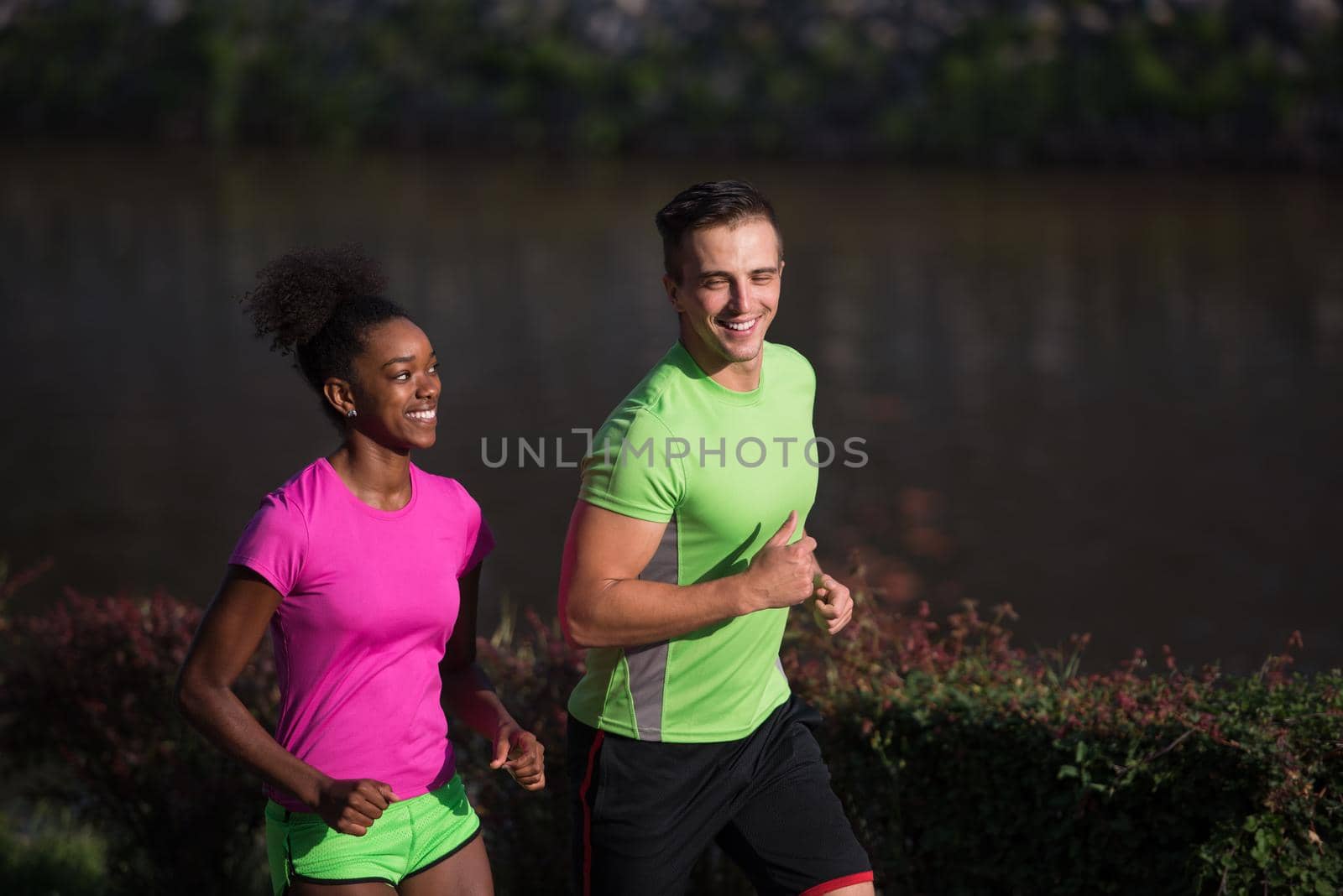 young smiling multiethnic couple jogging in the city by dotshock