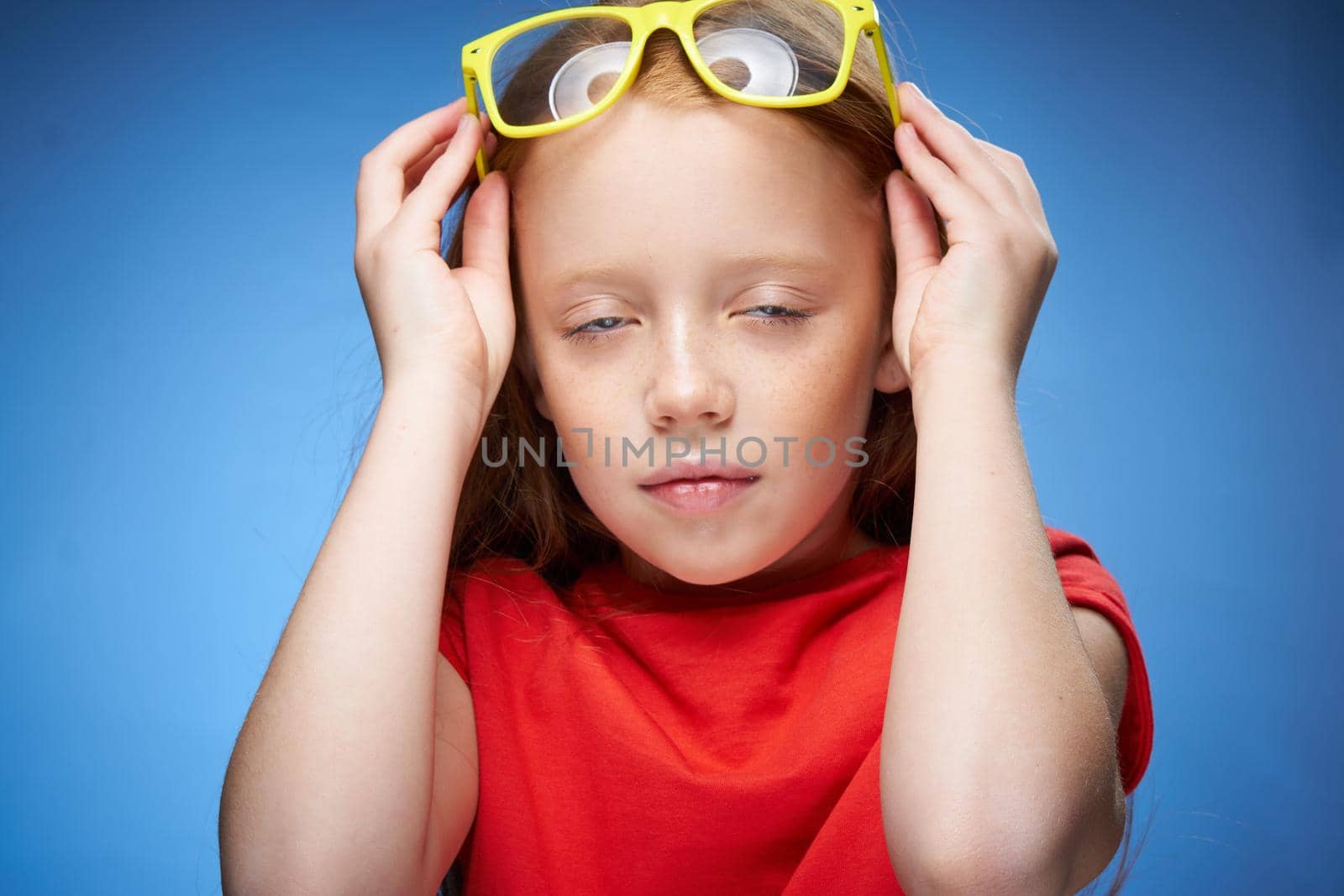 cute red-haired girl in red t-shirt emotions blue background. High quality photo
