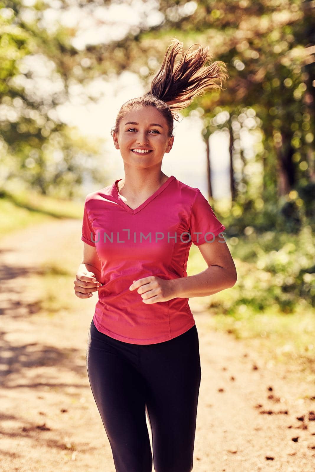 woman enjoying in a healthy lifestyle while jogging on a country road through the beautiful sunny forest, exercise and fitness concept