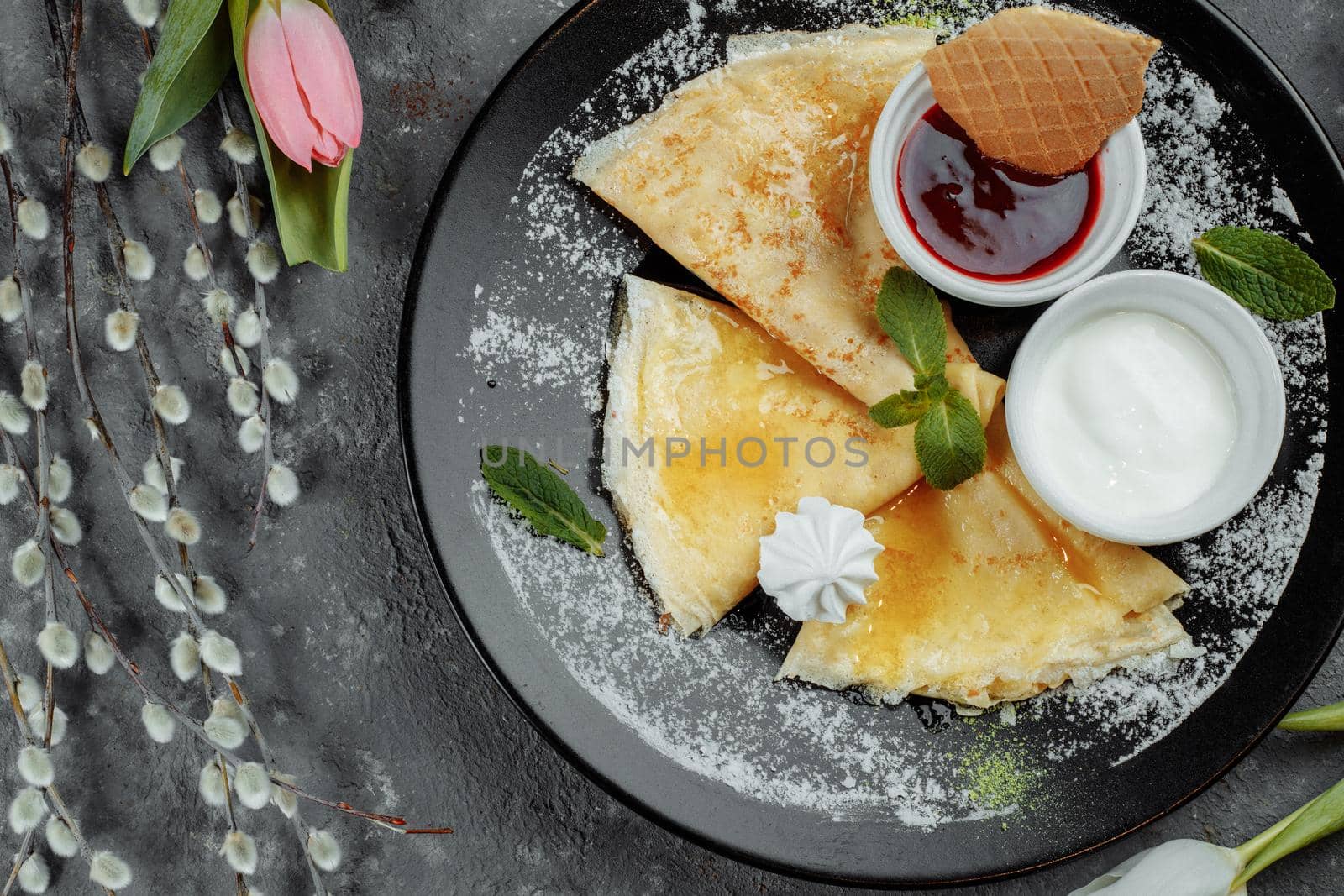 Pancakes with strawberries and creme black plate.