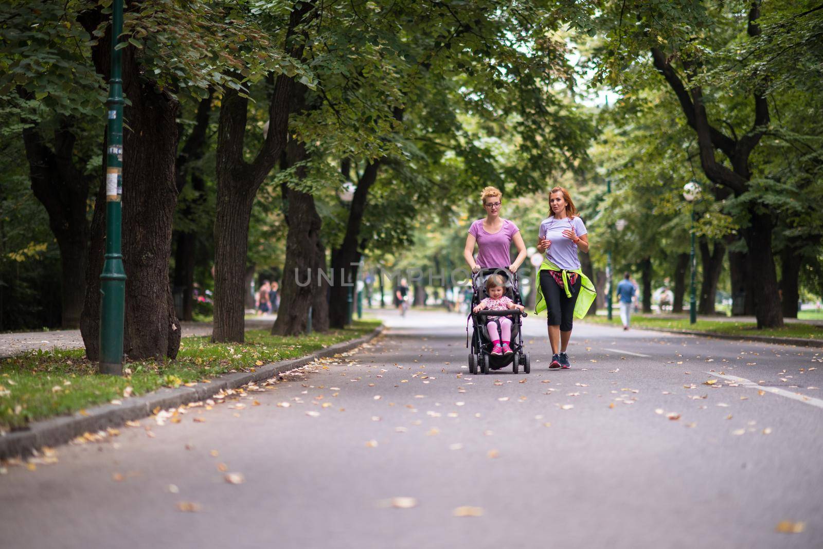 women with baby stroller jogging together by dotshock