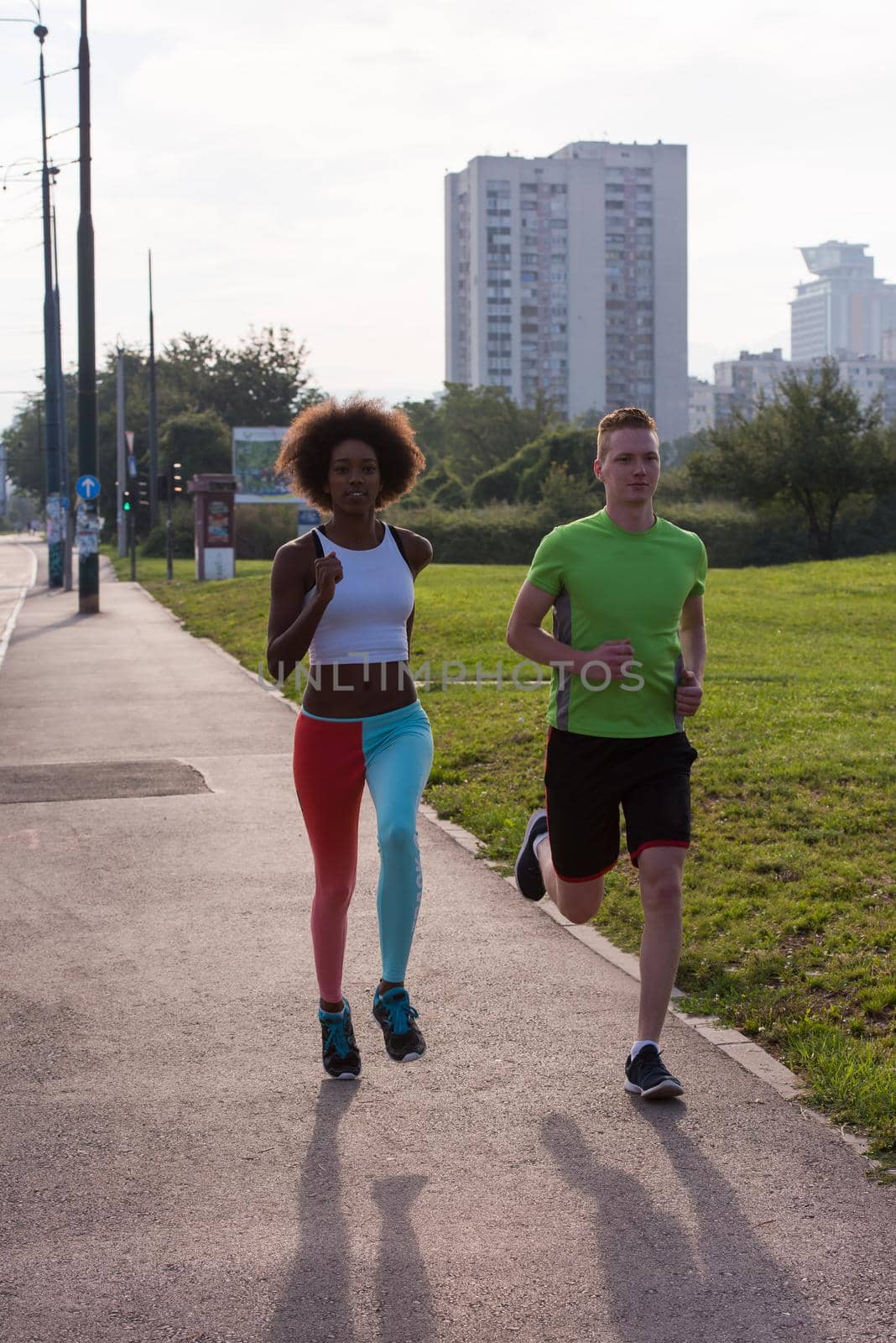 multiethnic group of young people on the jogging beautiful morning as the sun rises in the streets of the city