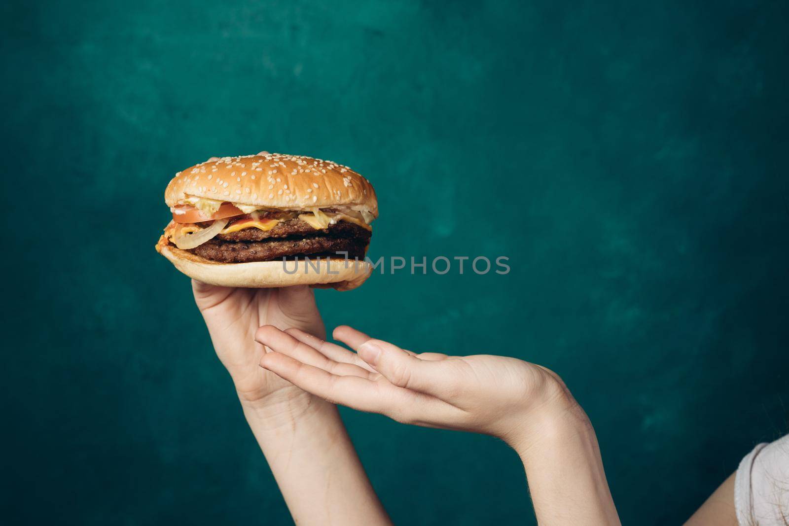 hamburger in hands close-up fast food green background by Vichizh