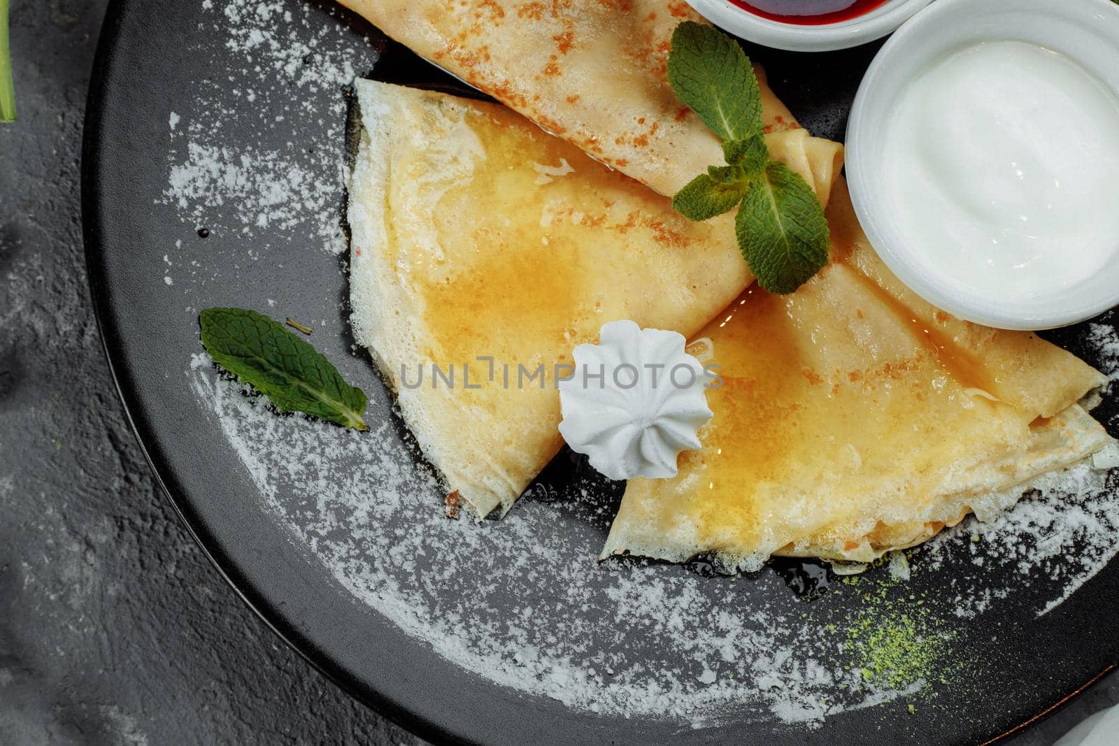 Pancakes with strawberries and creme black plate.