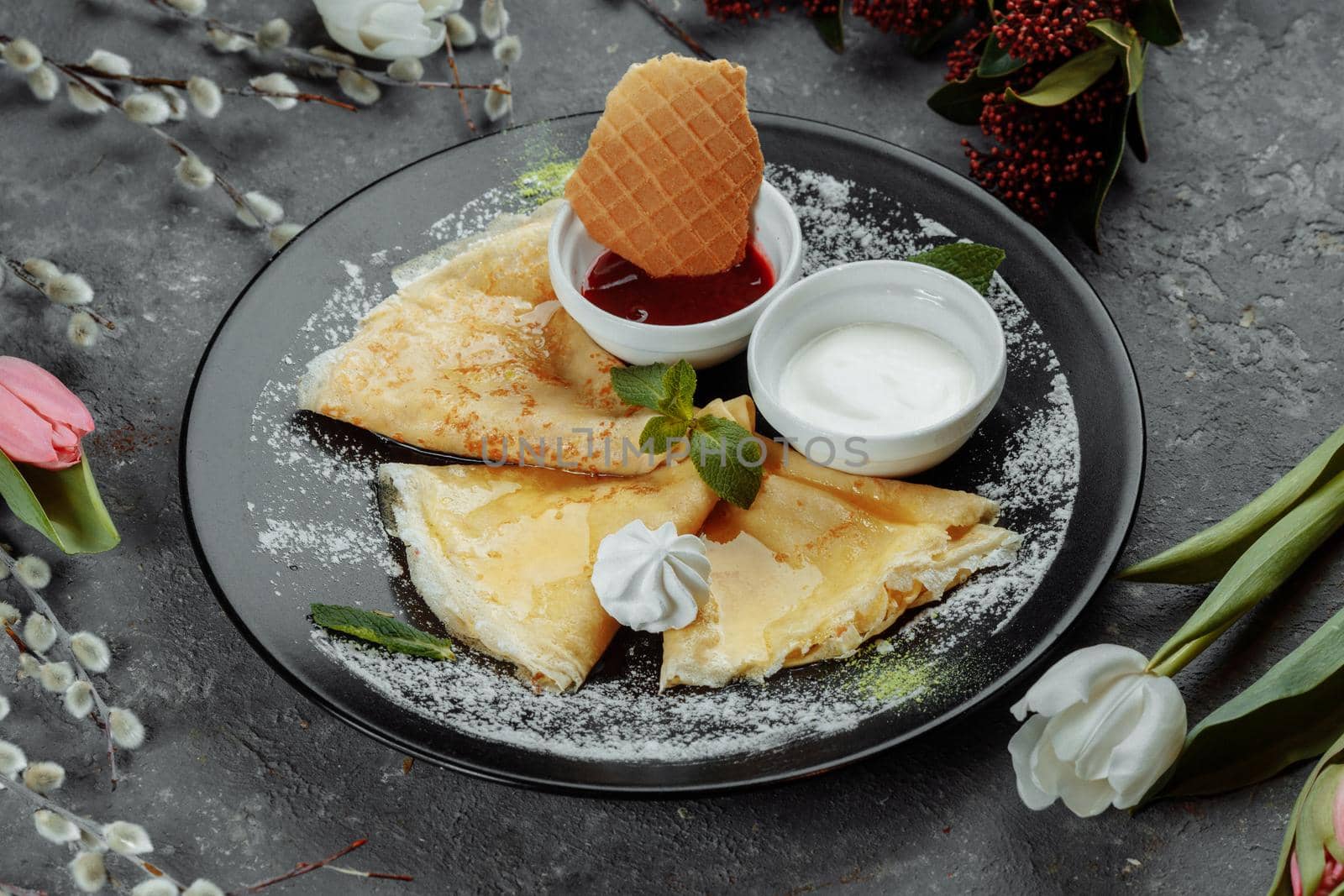 Pancakes with strawberries and creme black plate.