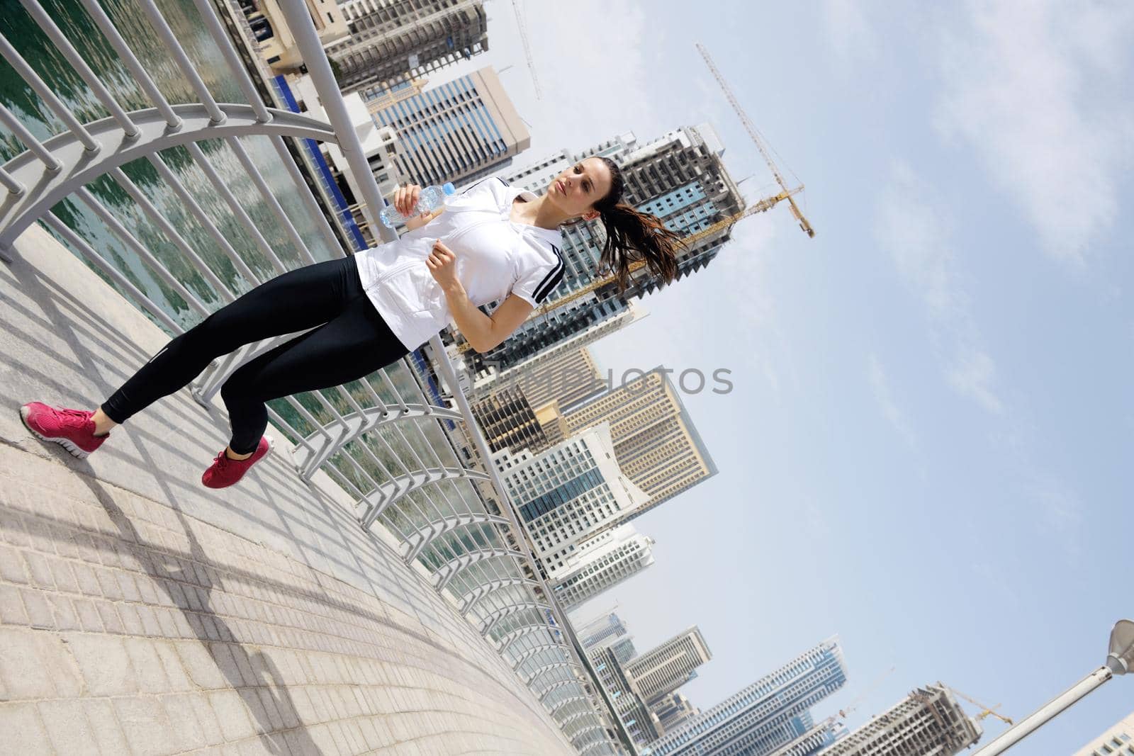 Running in city park. Woman runner outside jogging at morning with Dubai urban scene in background