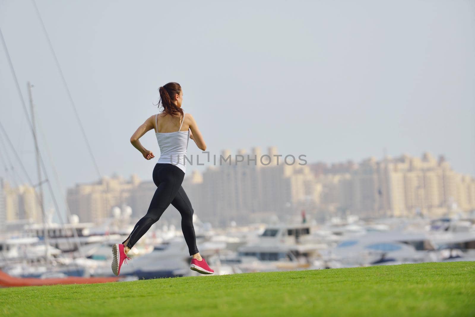 Running in city park. Woman runner outside jogging at morning with Dubai urban scene in background