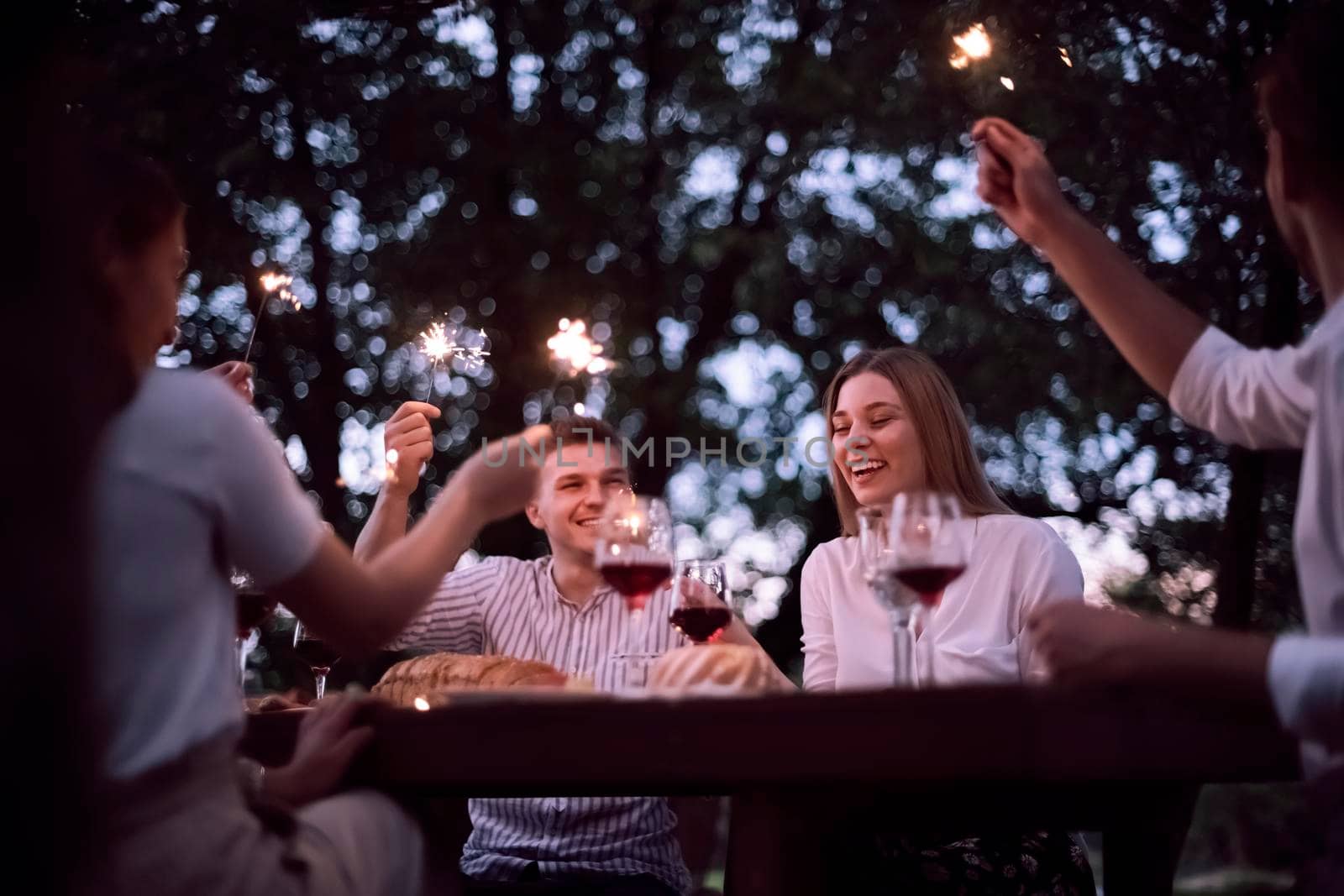 group of happy friends having picnic french dinner party outdoor during summer holiday vacation near the river at beautiful nature