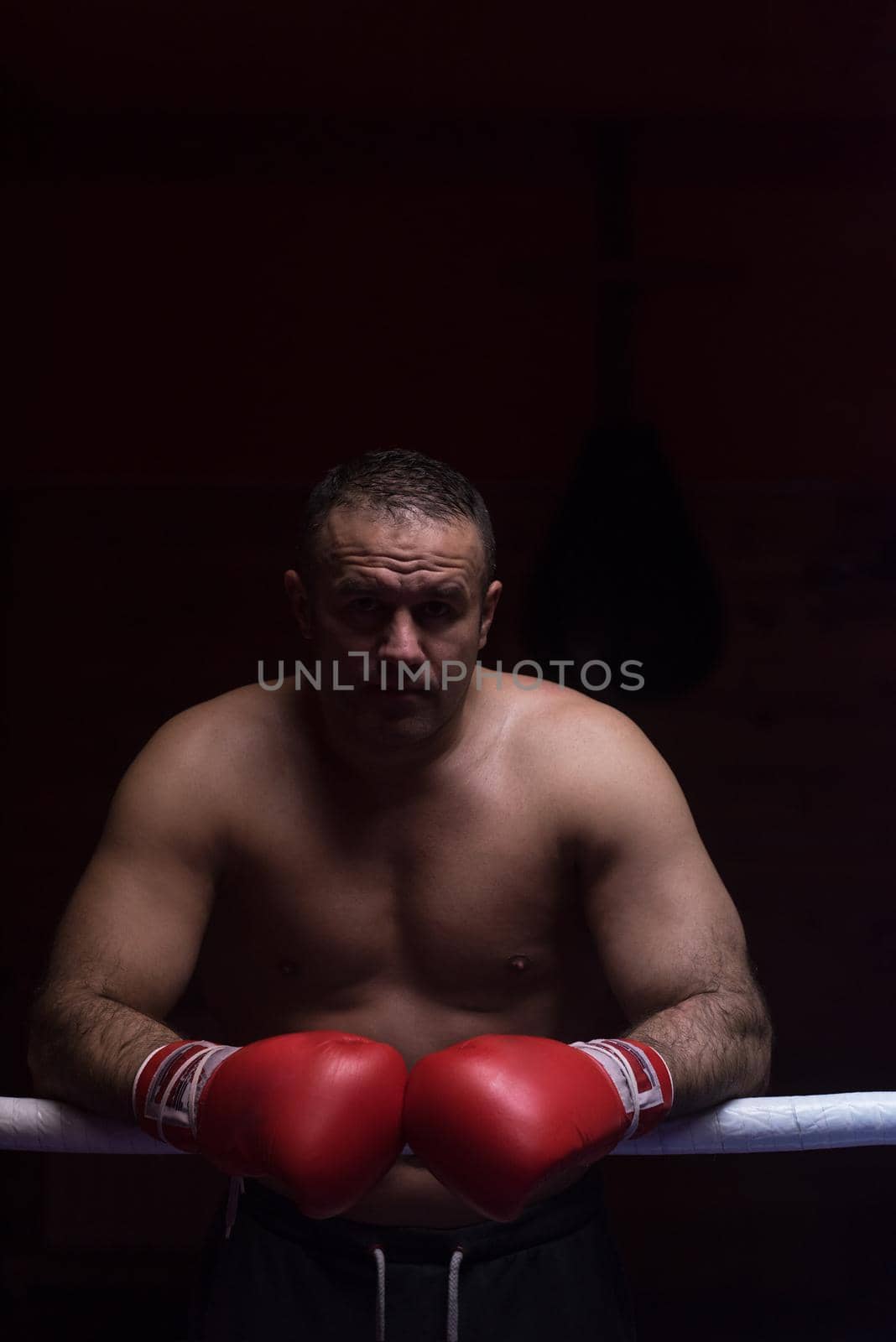 portrait of muscular professional kickboxer who standing in the ring while training for the fight