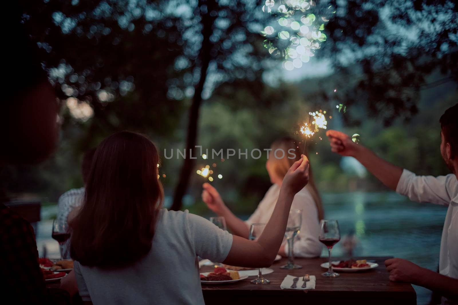 group of happy friends having picnic french dinner party outdoor during summer holiday vacation near the river at beautiful nature